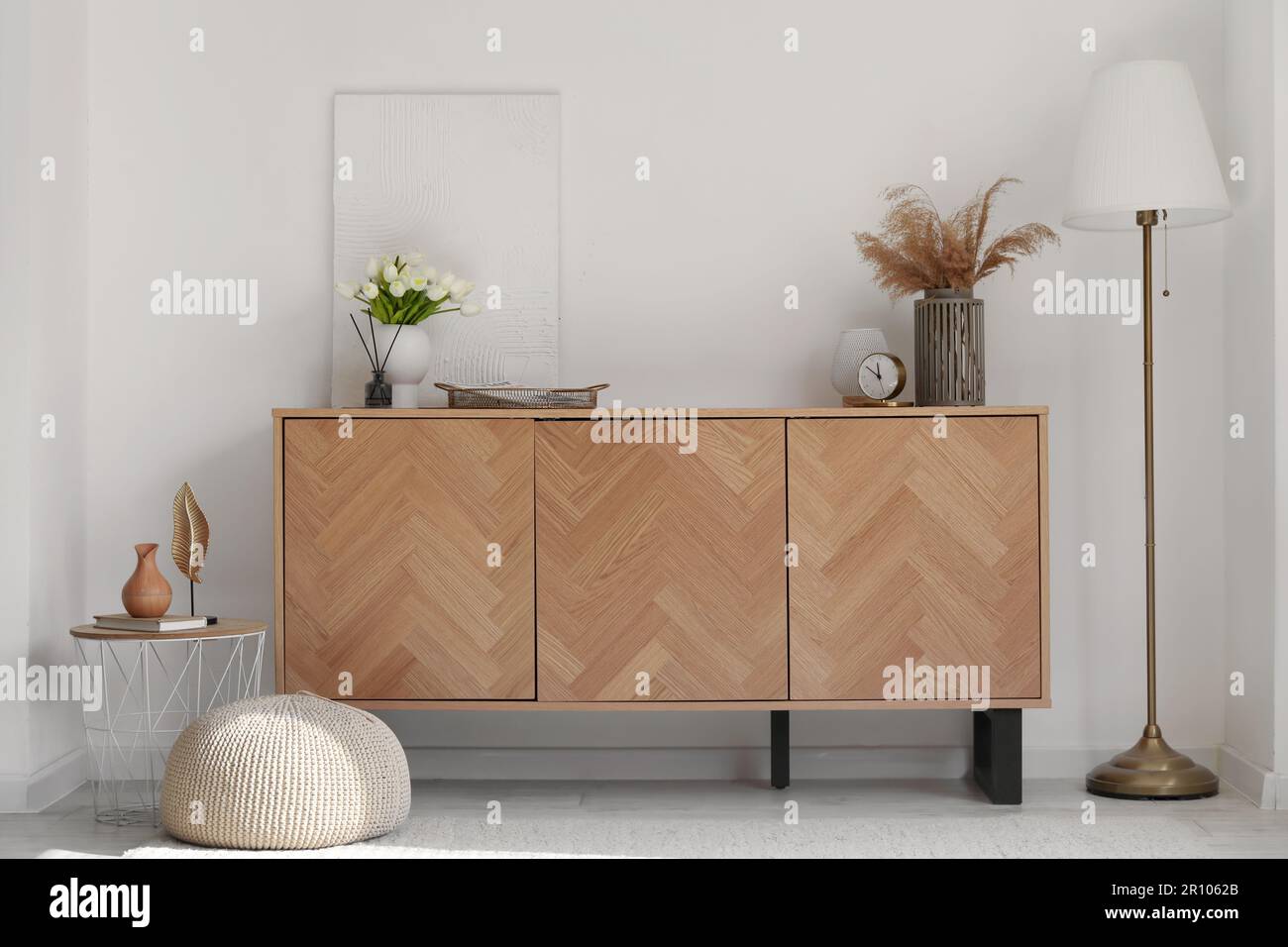 Stylish wooden cabinet with pampas grass and tulip flowers in interior ...