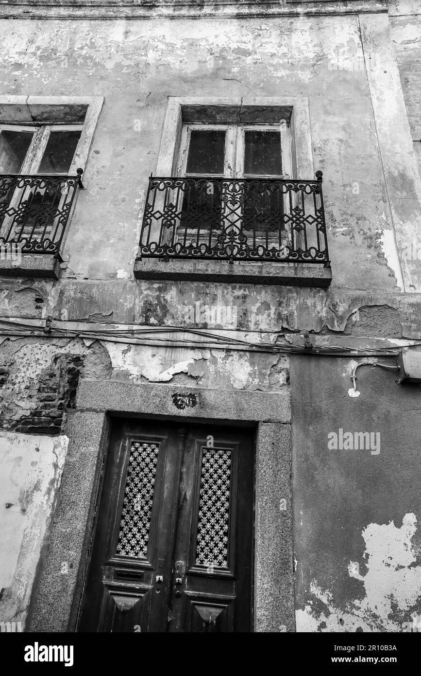 Old house with white chipped facade and wooden windows in Evora town ...
