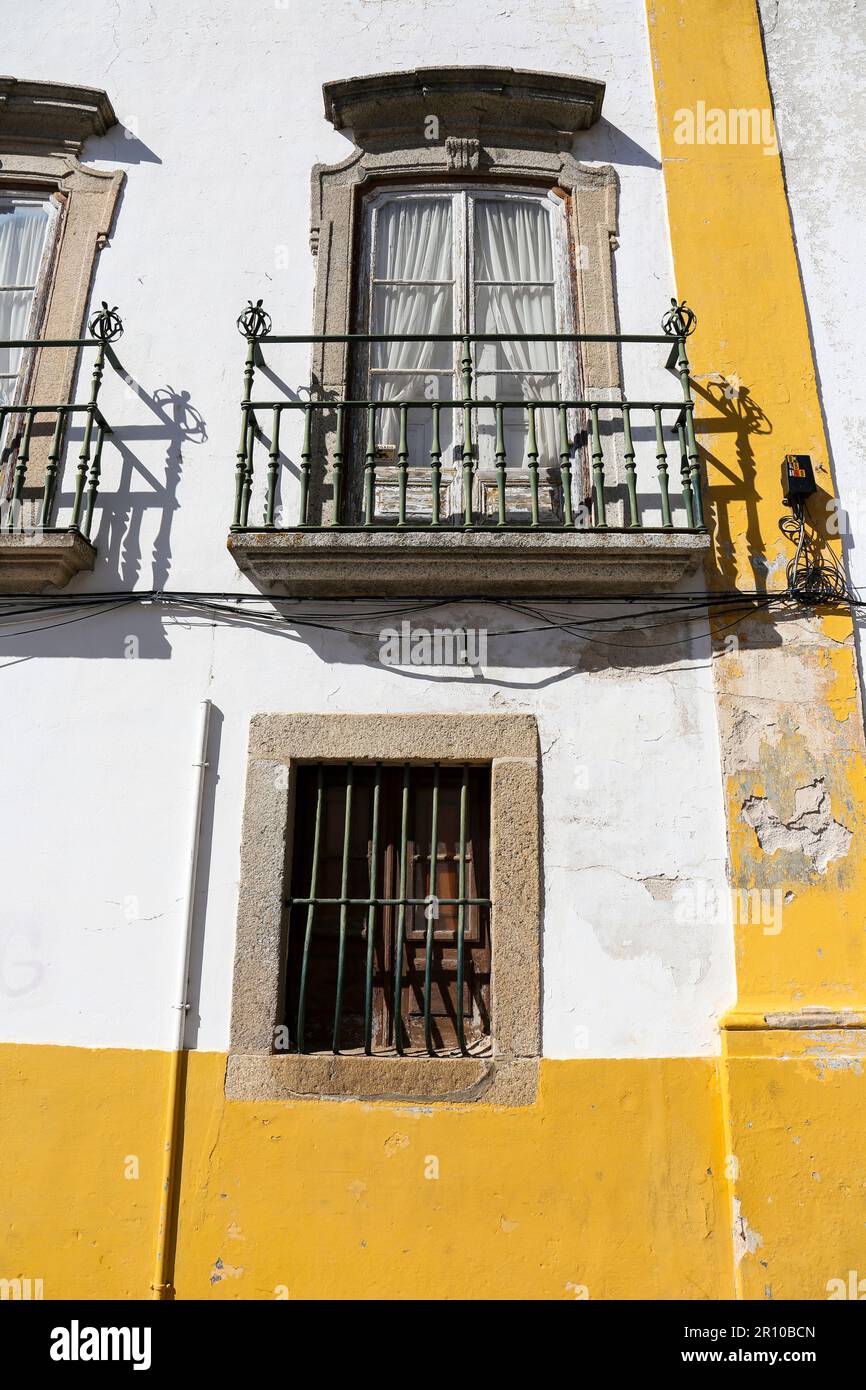Old house with white chipped facade and wooden windows in Evora town ...
