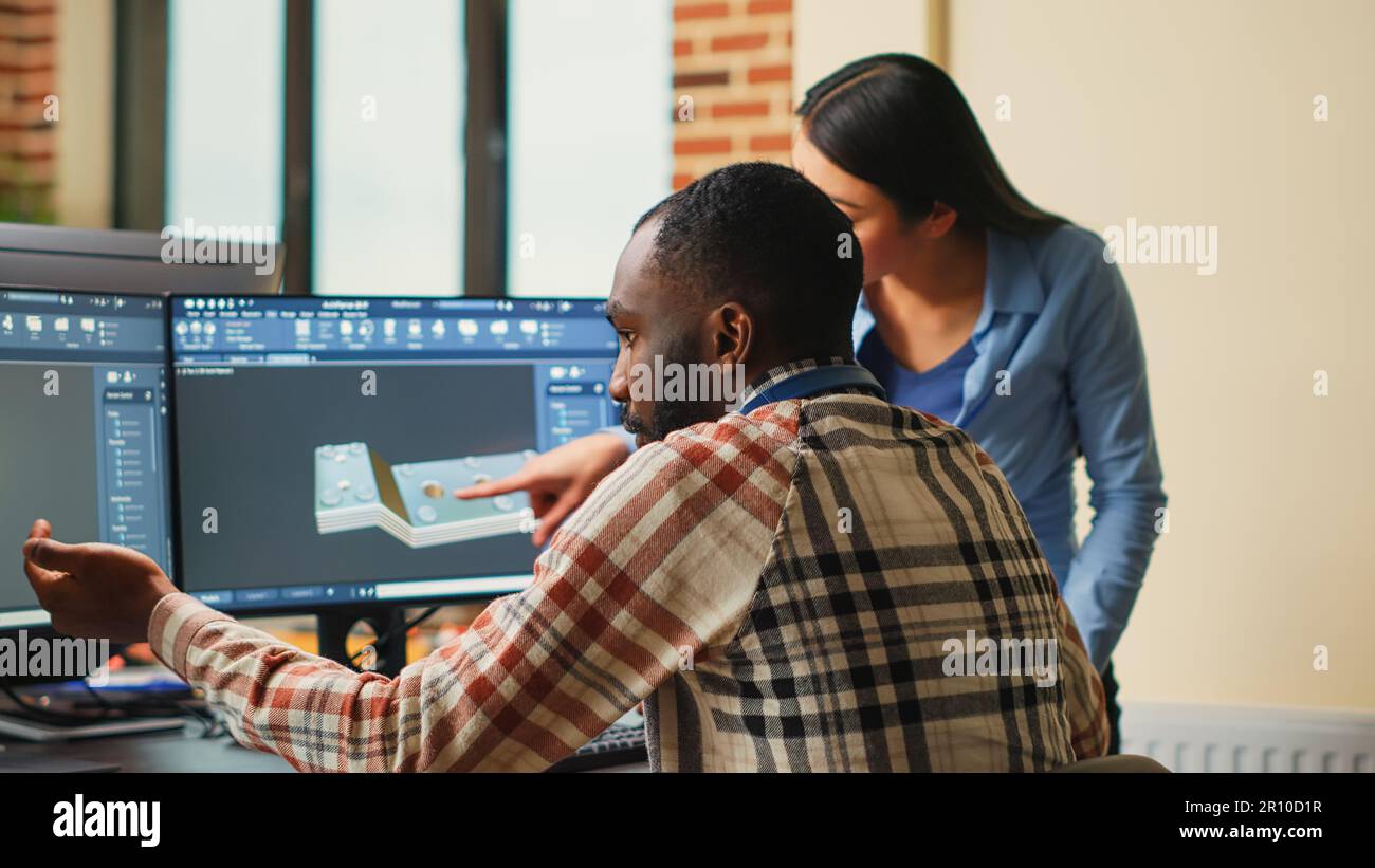 Artistic digital technicians talking about machine development, working together on clamp prototype. Professional graphic engineers developing industrial engine product using specialized software. Stock Photo