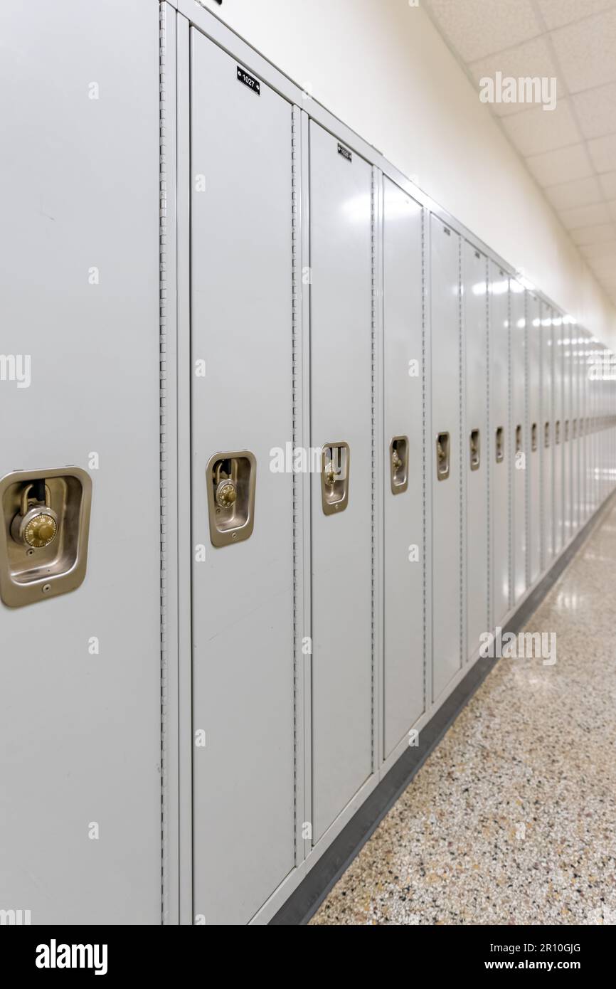 Vertical photo of an empty middle school or high school hallway with gray student lockers Stock Photo