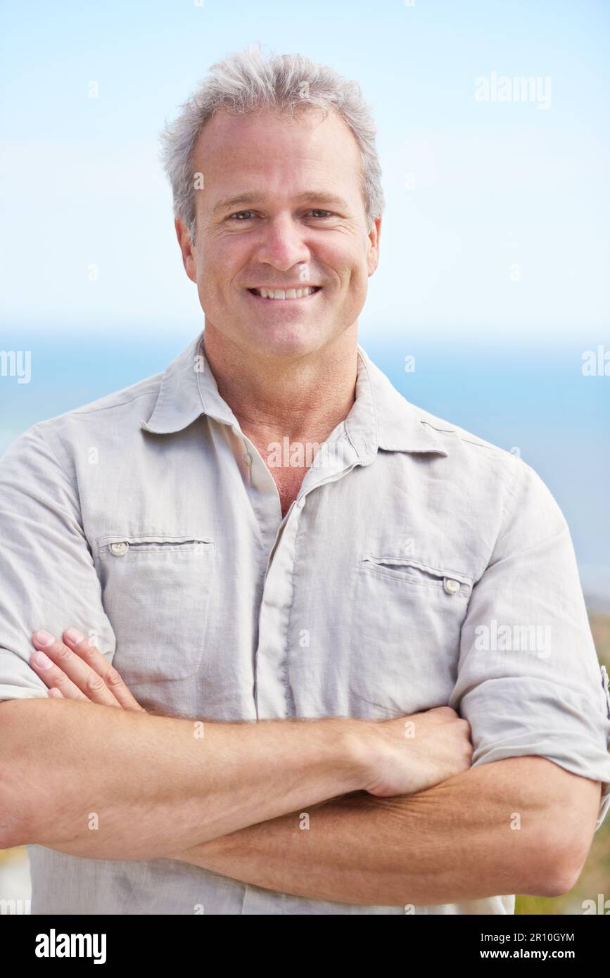 Enjoying some fresh sea air. Portrait of a mature man smiling happily at the camera. Stock Photo