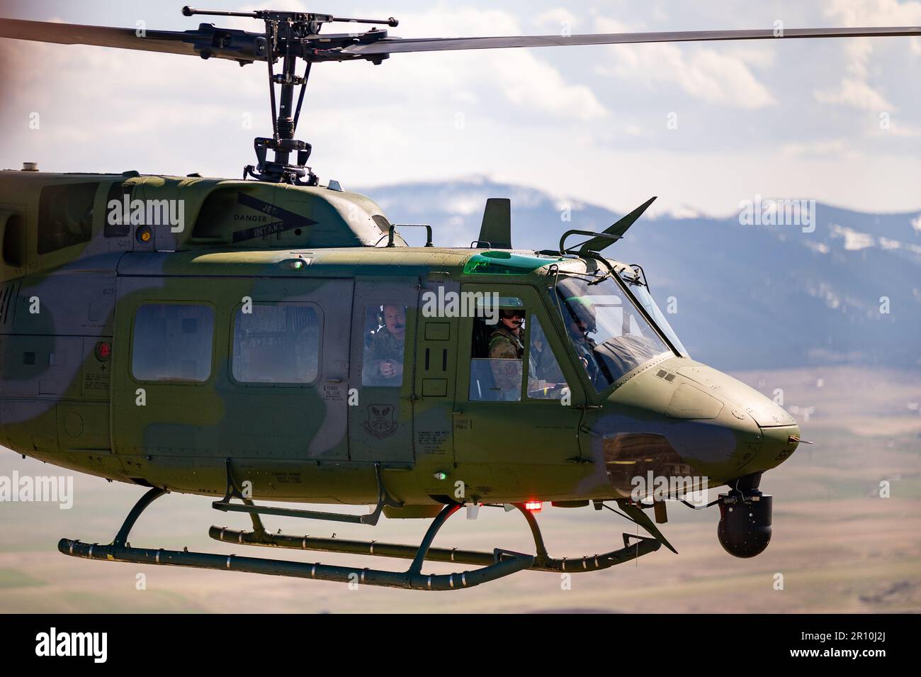 A 40th Helicopter Squadron UH-N1 Huey crew watch their counterpart midflight May 2, 2023, at Malmstrom Air Force Base, Mont. The 40th Helicopter Squadron, a tenant unit assigned to Malmstrom Air Force Base, Montana, began as Detachment 5 of the 37th Air Rescue and Recovery Squadron and was one of seven detachments in the 37th ARRS under Military Airlift Command.  The 37th ARRS was activated during the Korean War when helicopters were first used for medical evacuation. After the Vietnam War, 37th ARRS was deactivated, only to be reactivated in December 1973. (U.S. Air Force photo by Airman 1st Stock Photo