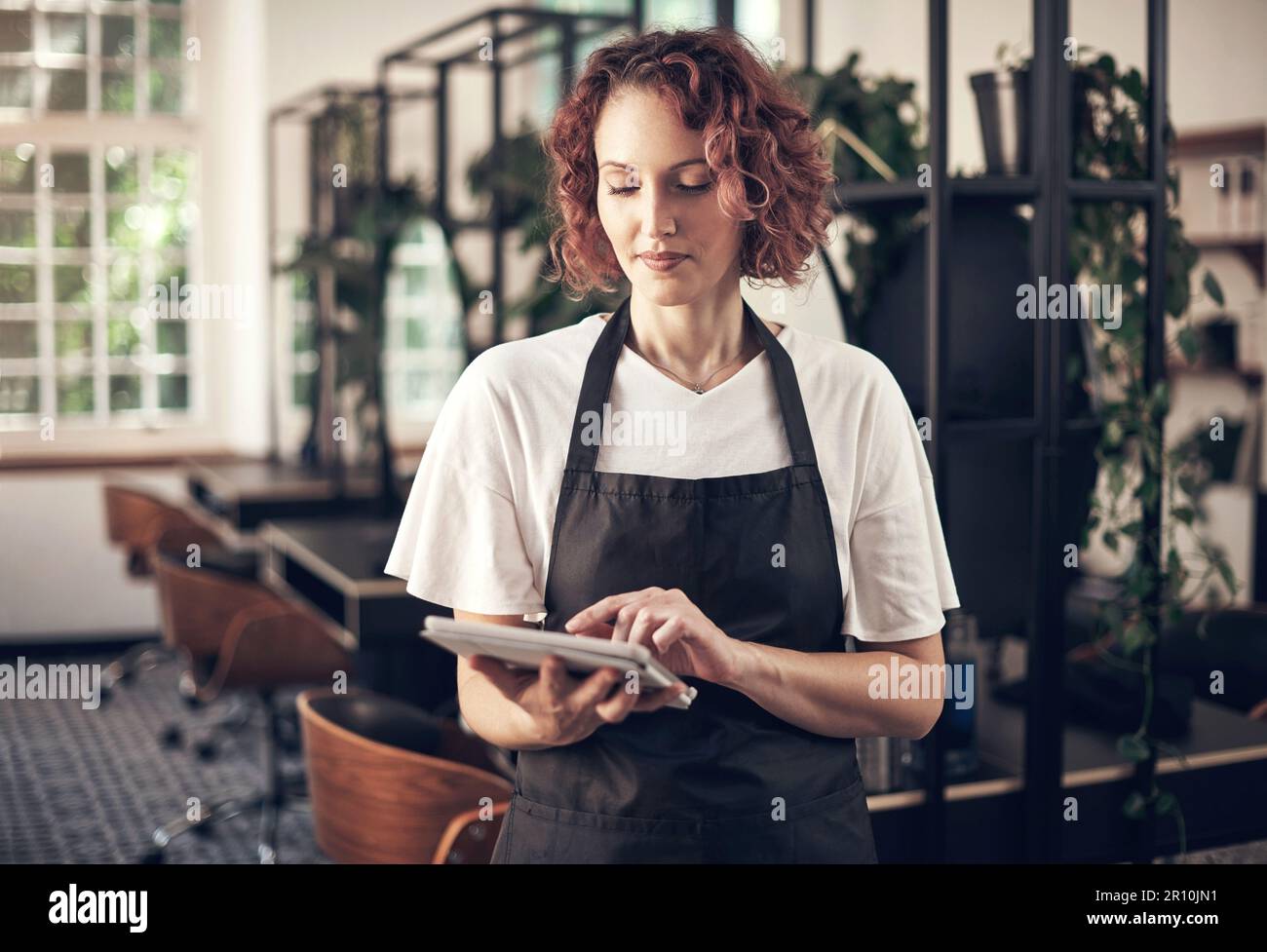 This makes attracting clients to my salon a little easier. a hairstylist using a digital tablet at work. Stock Photo