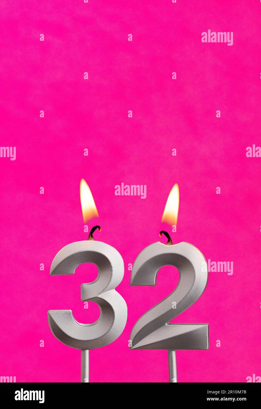 Candle 32 with flame - Silver anniversary candle on a fuchsia background Stock Photo