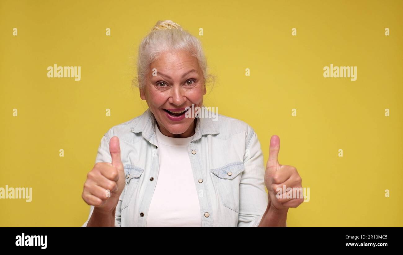 Elderly European woman shows a thumbs up, approving the choice Stock Photo