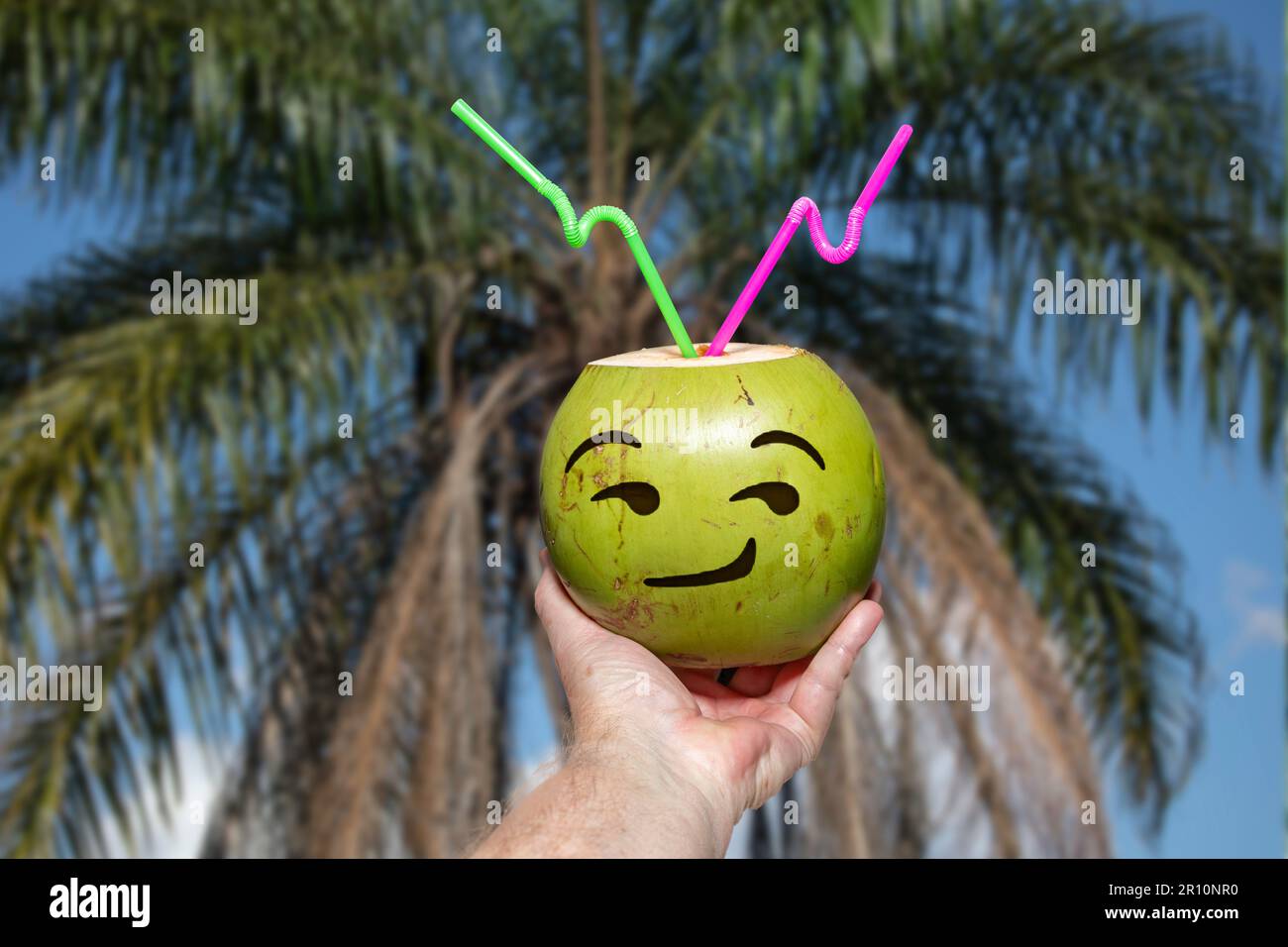 Green coconut with drawn emoji. tropical coconut water in selective focus. artistic photo Stock