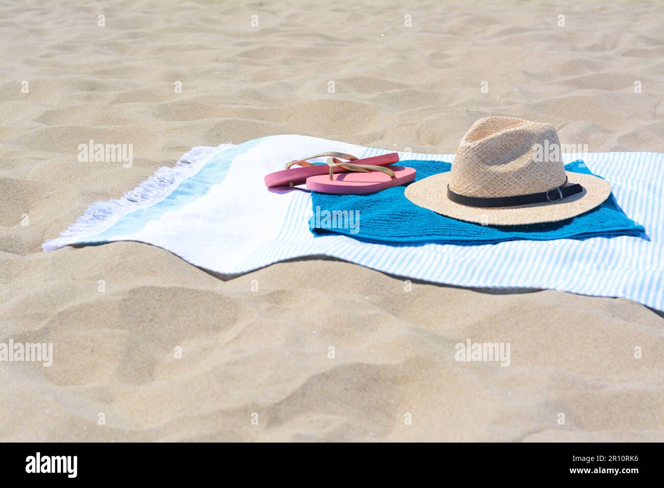 BLue towels, flip flops and straw hat on sandy beach Stock Photo - Alamy