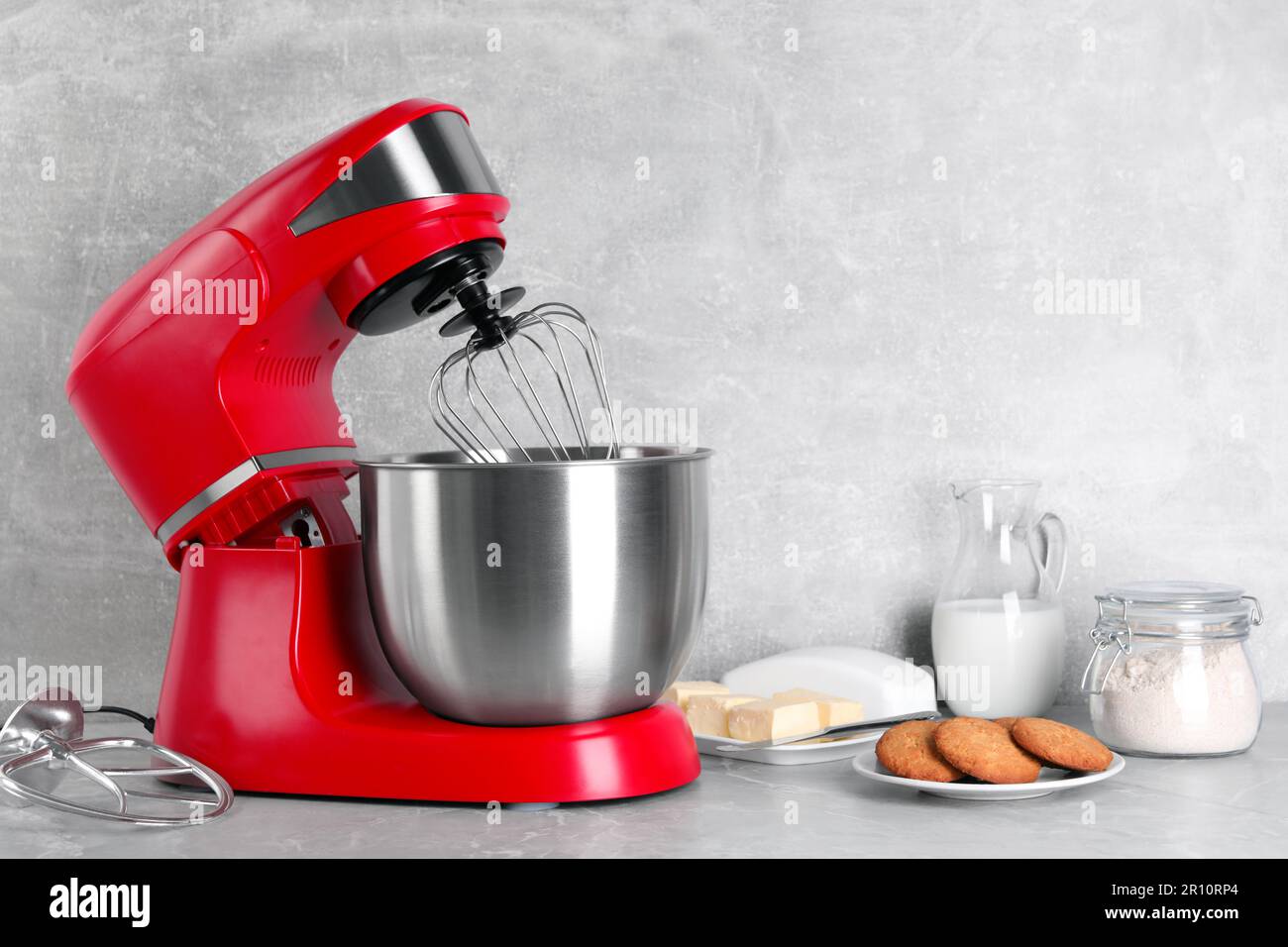 Modern red stand mixer, cookies and ingredients on light gray marble