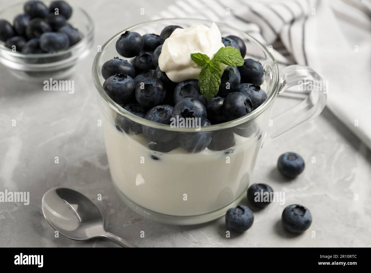 Delicious yogurt with blueberries served on grey marble table, closeup Stock Photo