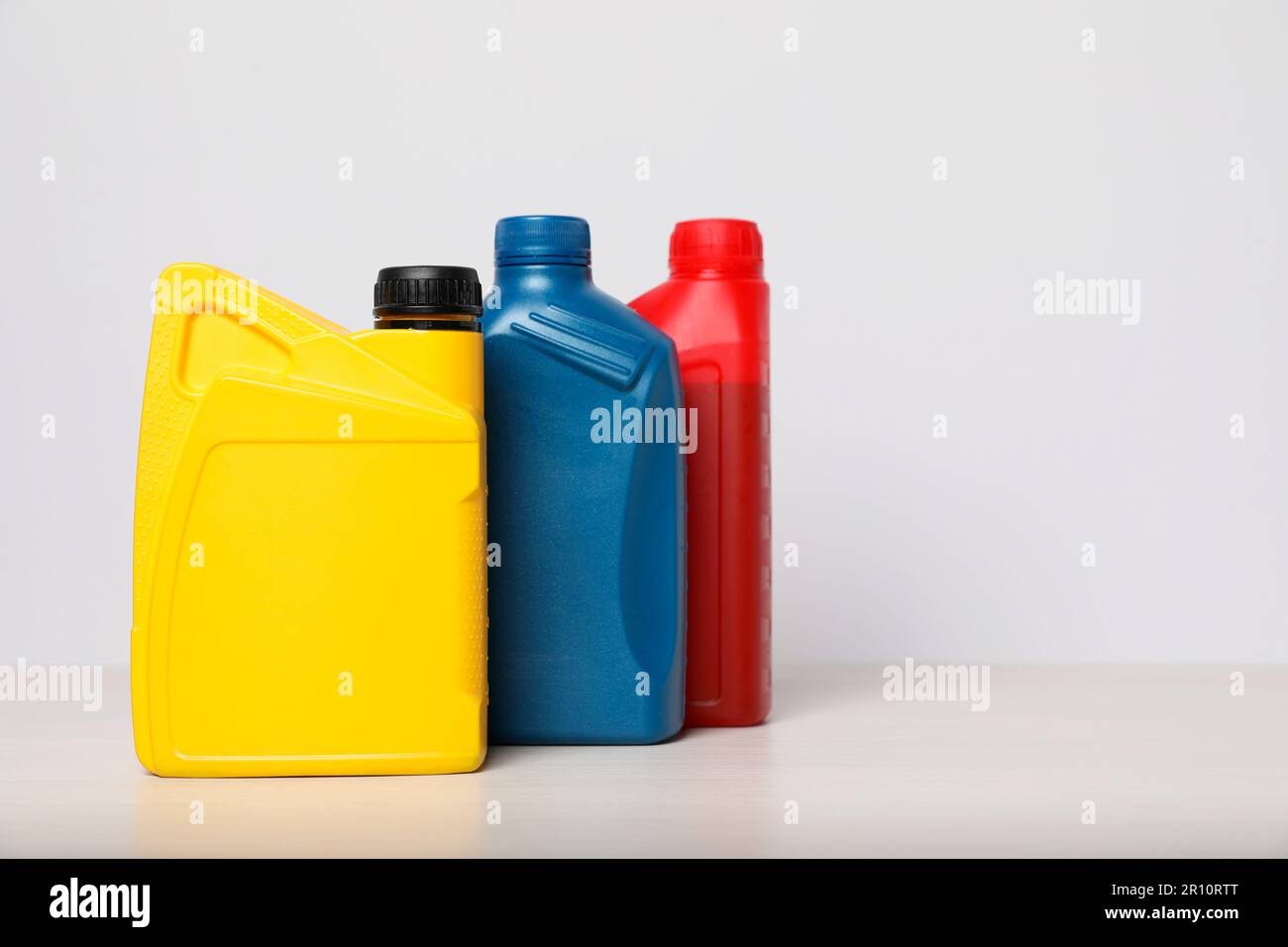 Motor oil in different canisters on table against white background