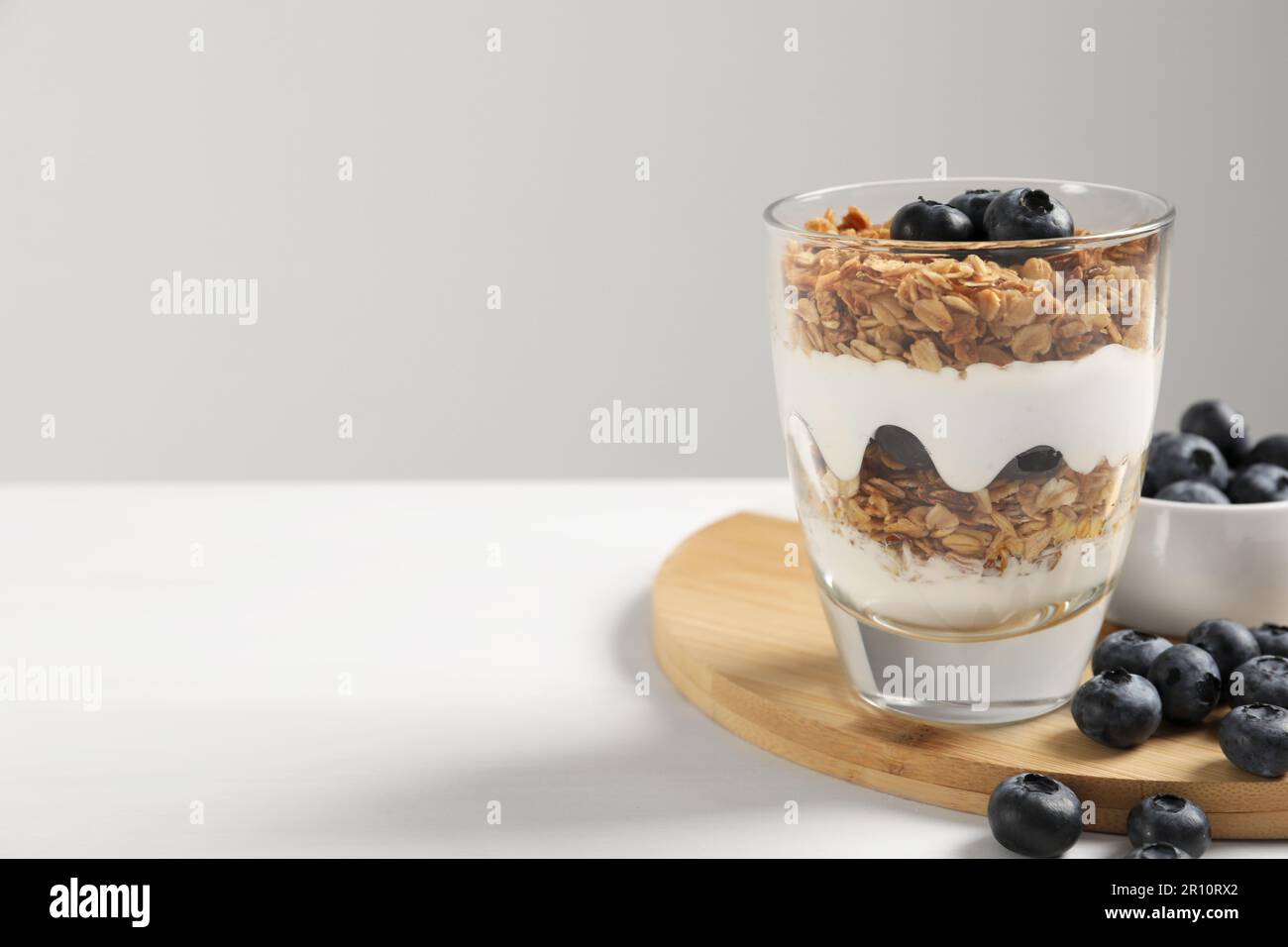Yogurt served with granola and blueberries on white wooden table, space for text Stock Photo
