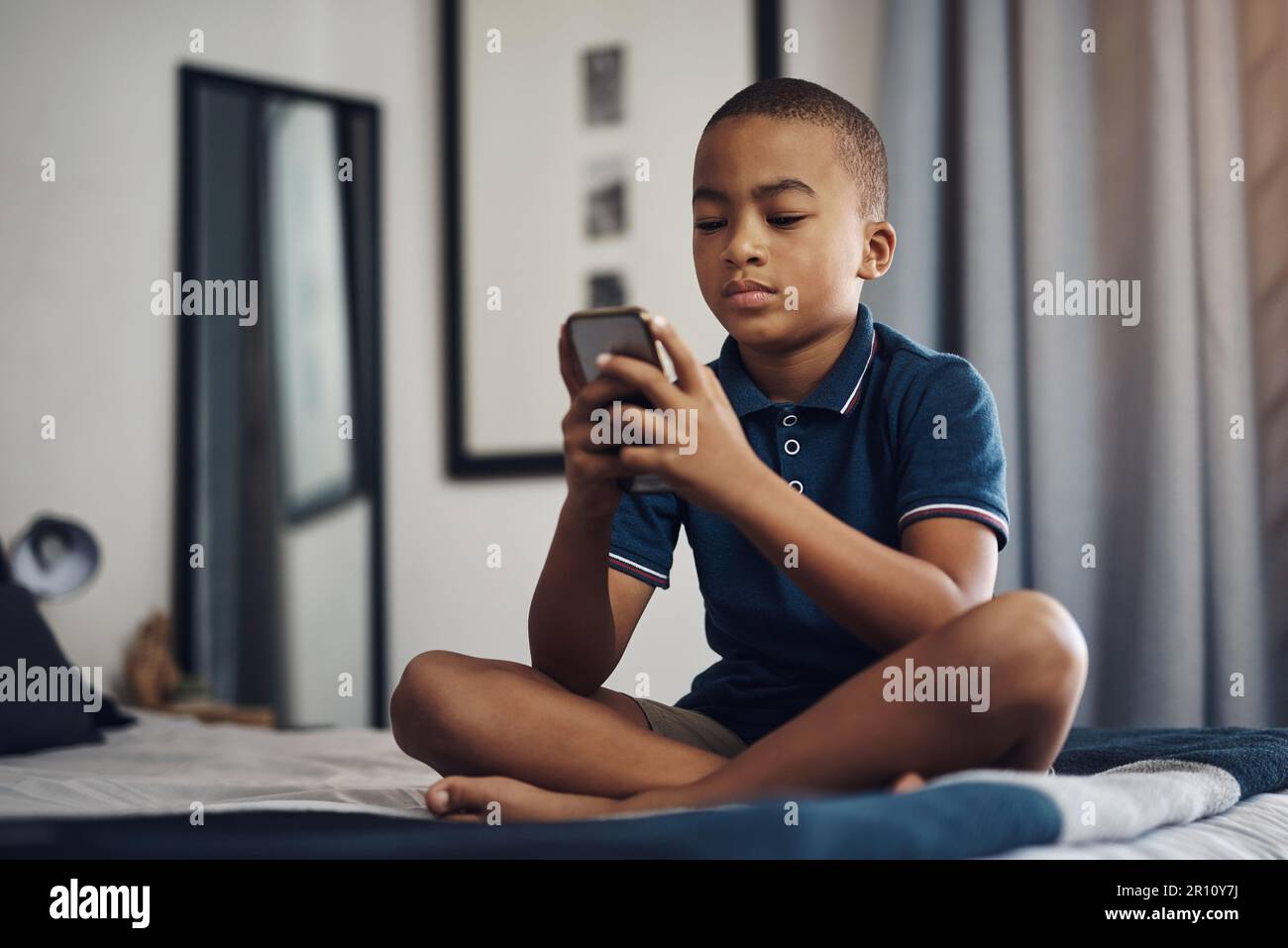 I use my screen time wisely. a young boy using a cellphone while ...