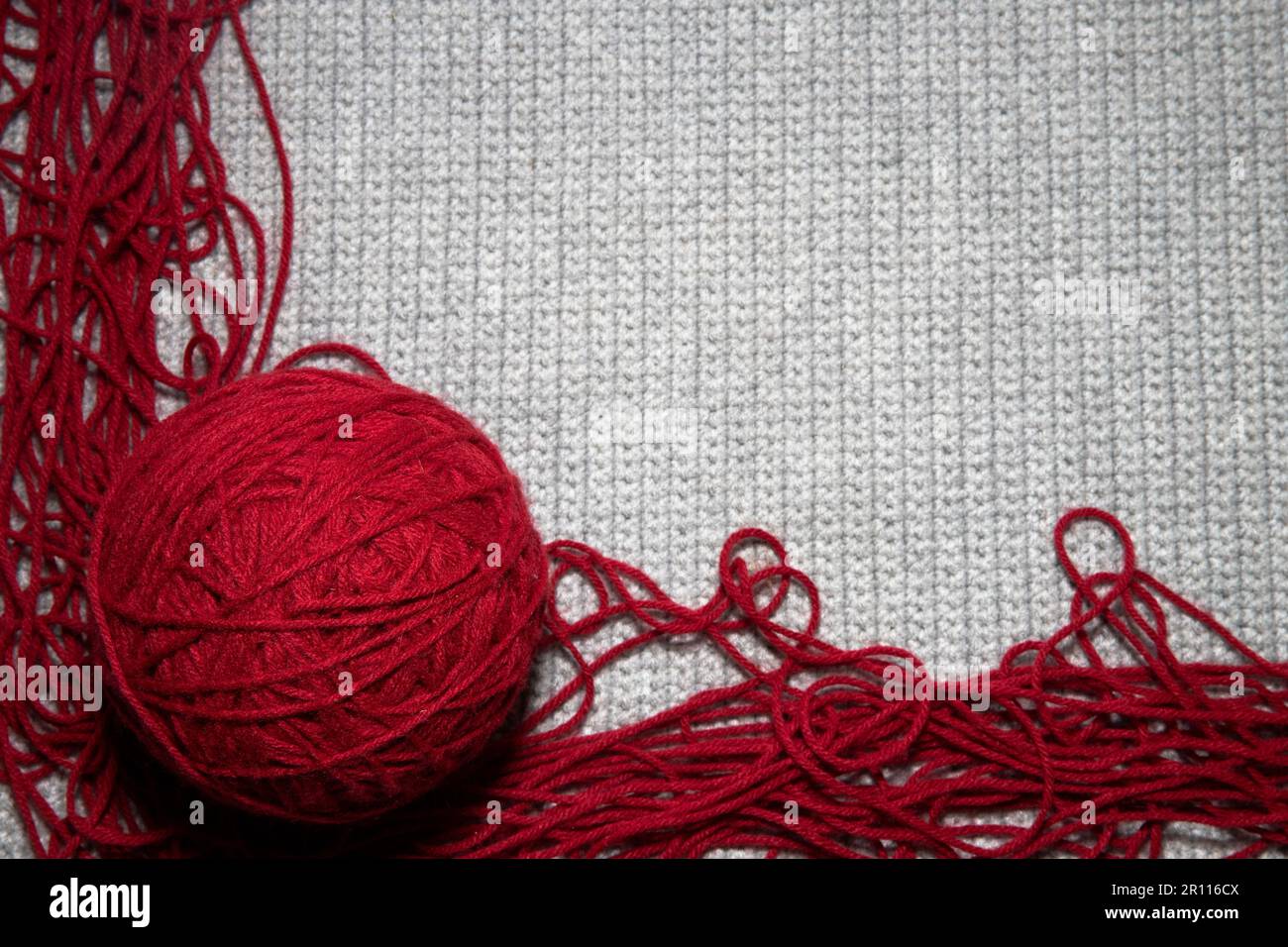 close up of gray knitted or crocheted tight knit blanket with a red