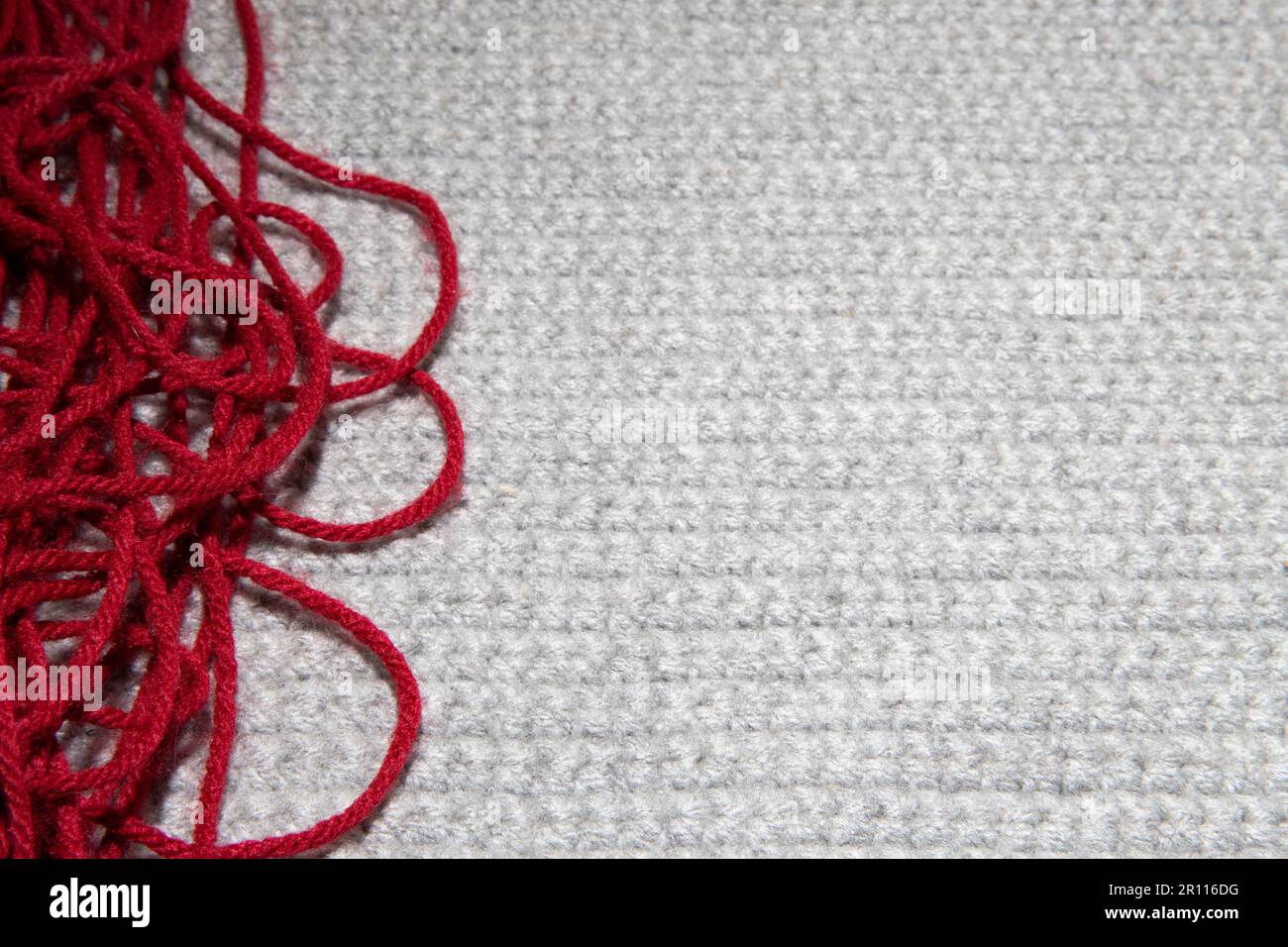 close up of gray knitted or crocheted tight knit blanket with a red