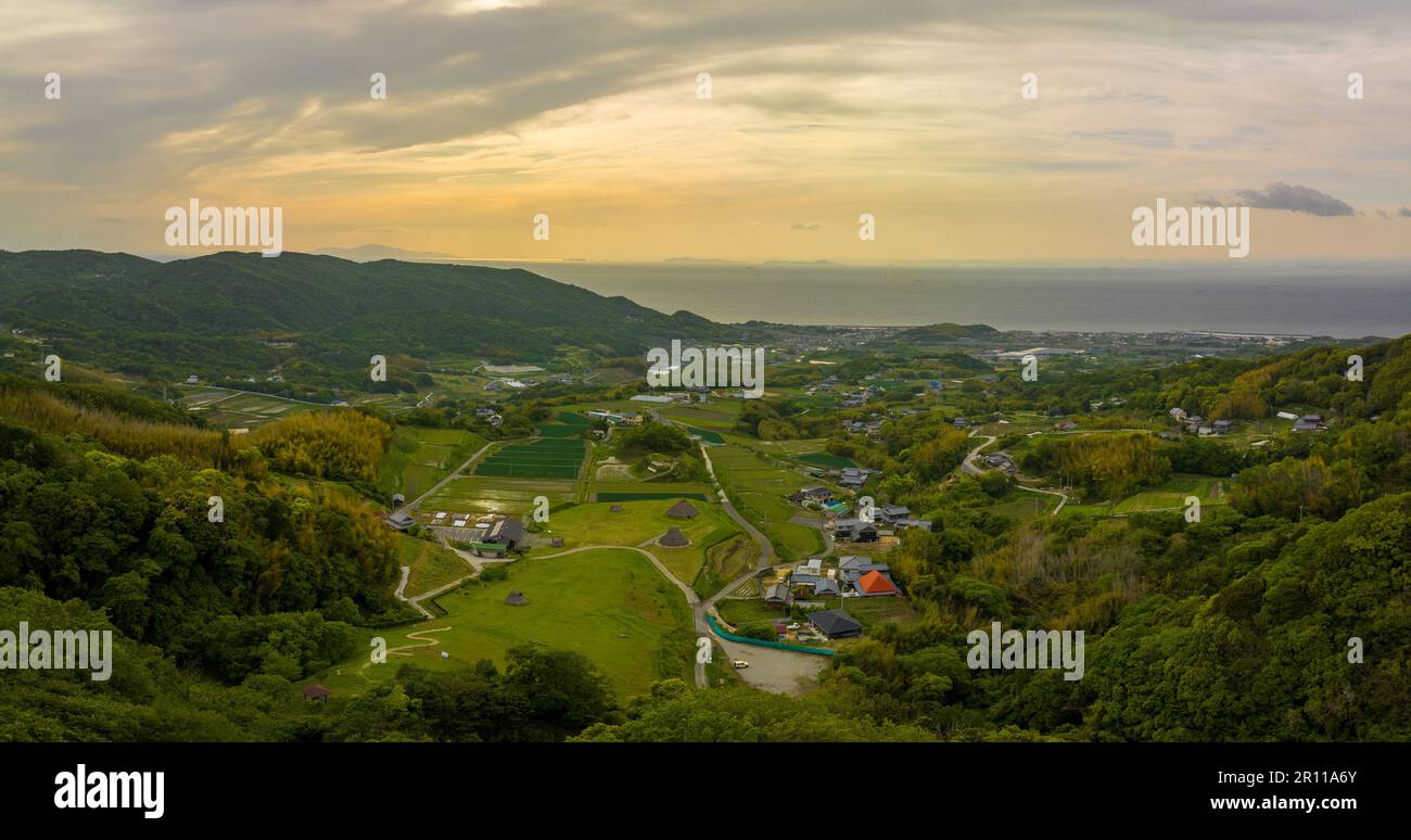 Panoramic aerial view of green fields and thatched huts in coastal landscape Stock Photo