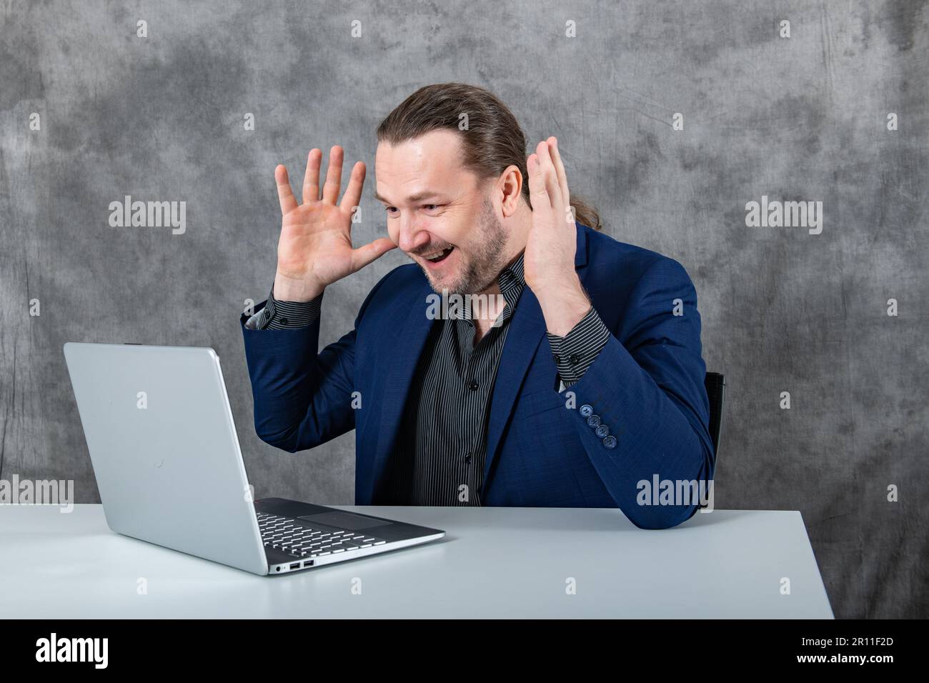 Surprised man working on laptop in blue suit Stock Photo