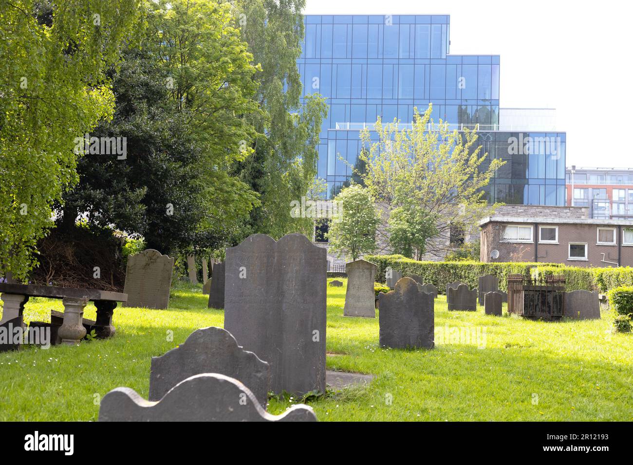 Modern buildings in the background and old grave stones from the cemetery at St. Michan's Church in Dublin, Ireland in foreground. Stock Photo