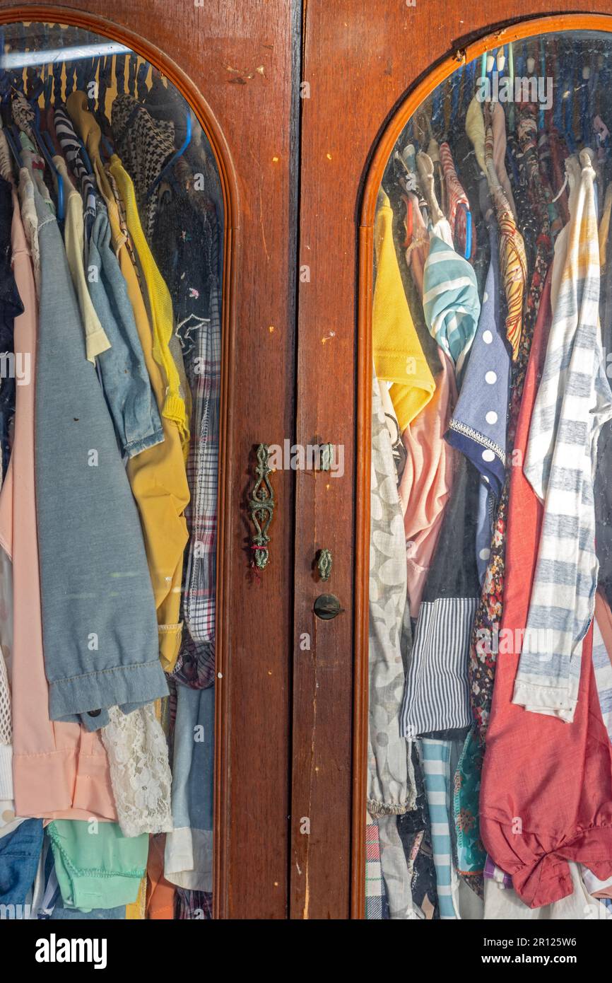 Clothes hang on hangers in an old wardrobe Stock Photo