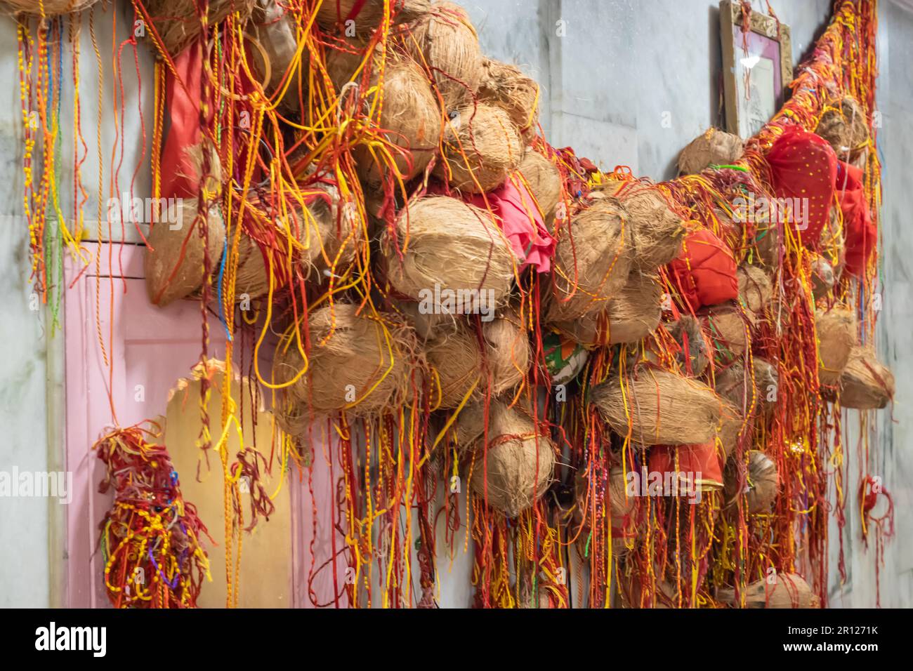 peeled coconut many tied with holy red threads at temple for god ...
