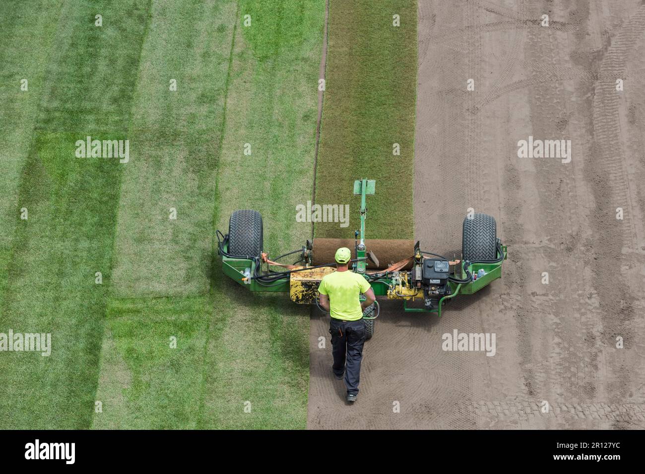 Workers laying grass in a roll on a football field at the stadium Stock
