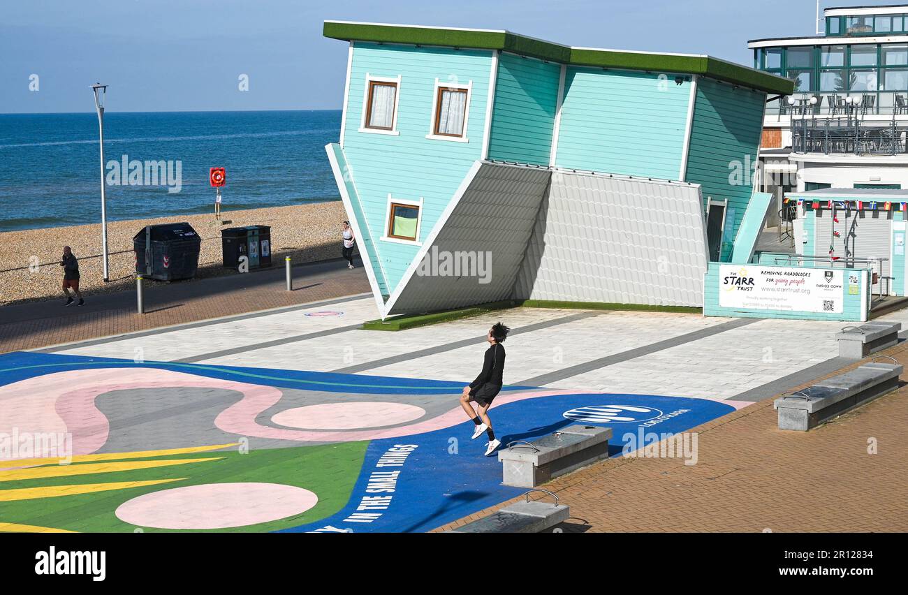 Brighton UK 11th May 2023 - Time for some early morning exercise by the Upside Down House on Brighton seafront ion a bright sunny morning along the South Coast : Credit Simon Dack / Alamy Live News Stock Photo