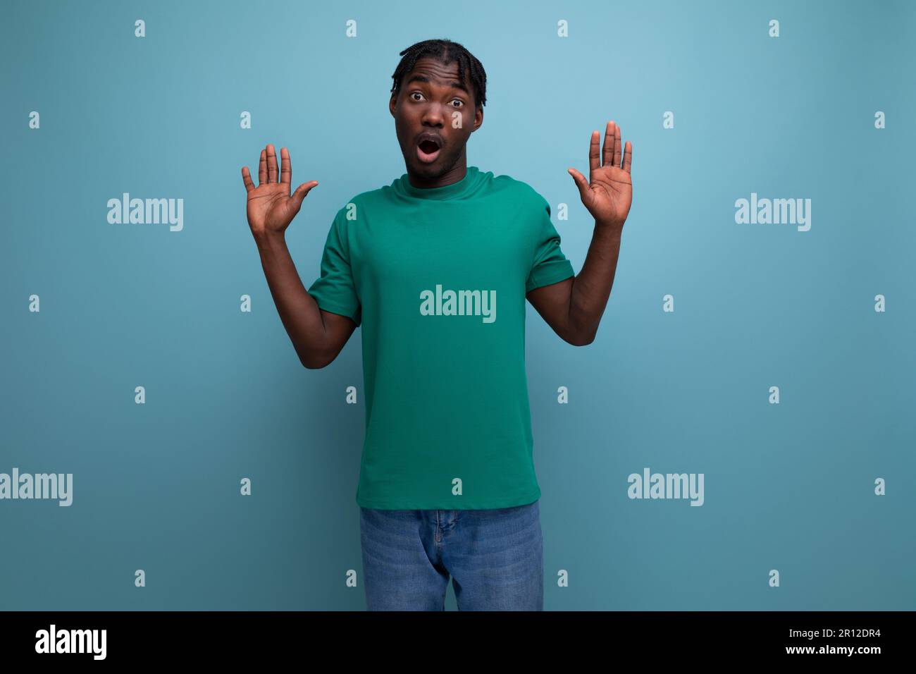 surprised confused brunette model stylish dark-skinned man in a t-shirt on a blue background Stock Photo