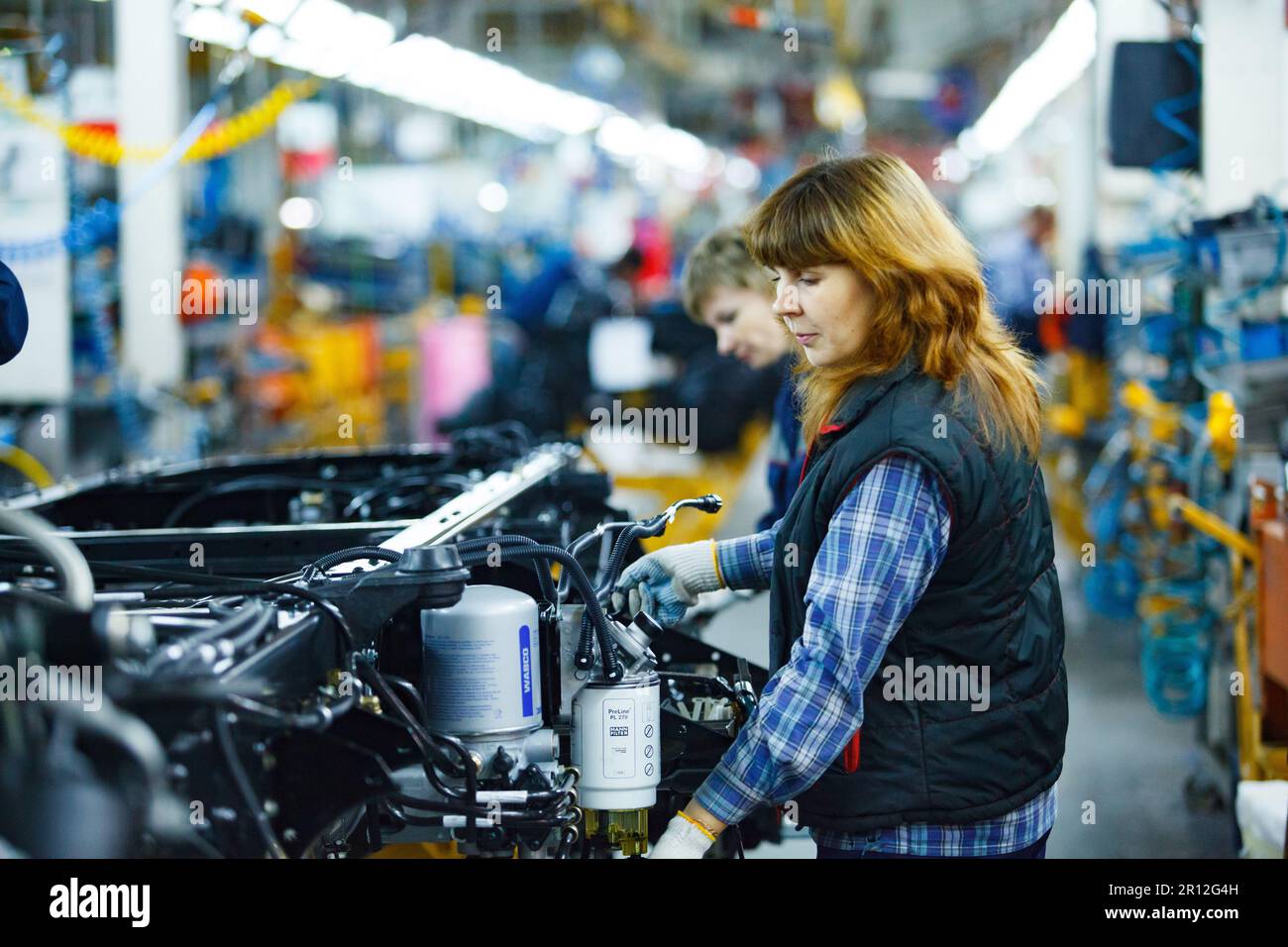 Nizhny Novgorod, Russia - November 21, 2020: GAZ car production plant. Young redhair woman assembling lorry. Stock Photo