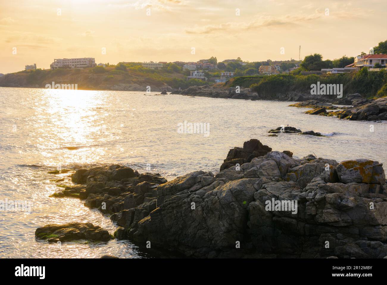 black sea scenery with rocks at sunrise. summer holiday season. cloudy weather. sunlight reflecting on the water surface Stock Photo