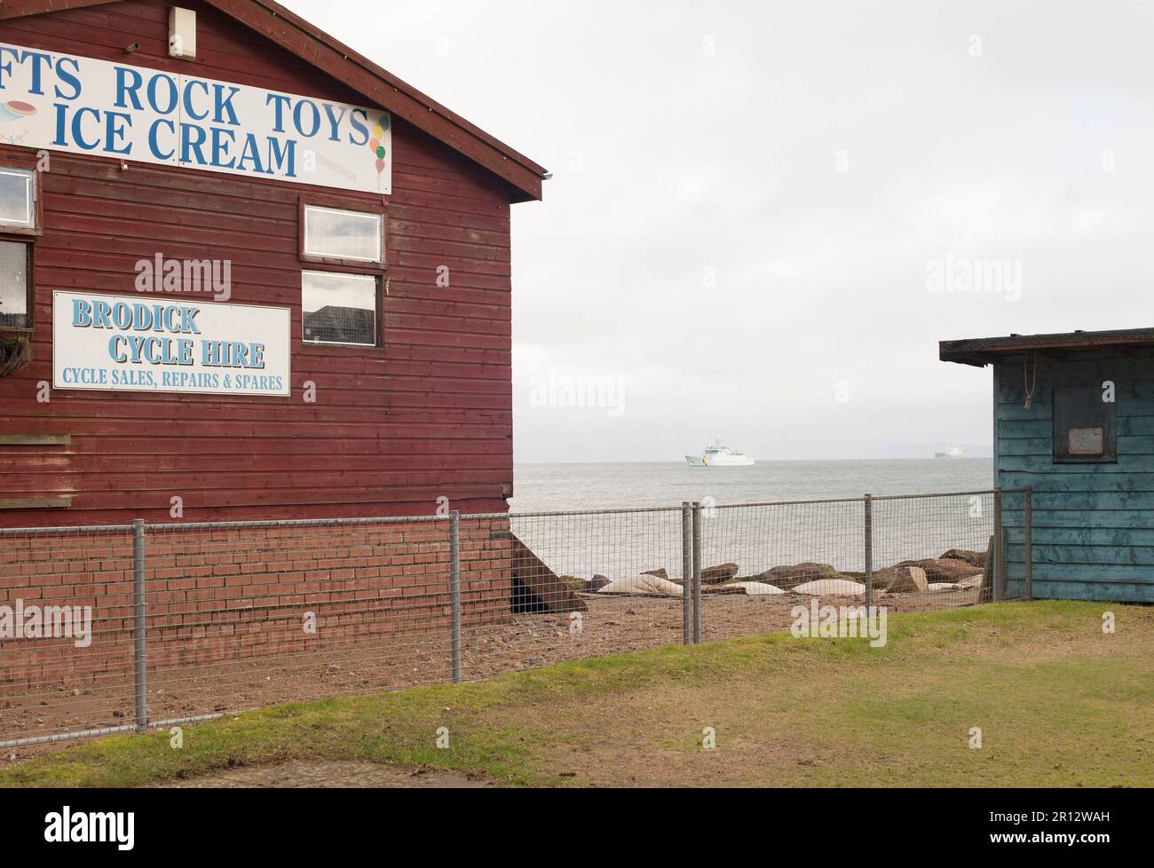 A cycle hire shop selling ice cream in Brodick on the Island of Arran in Scotland, looking out to ferries at sea. Stock Photo