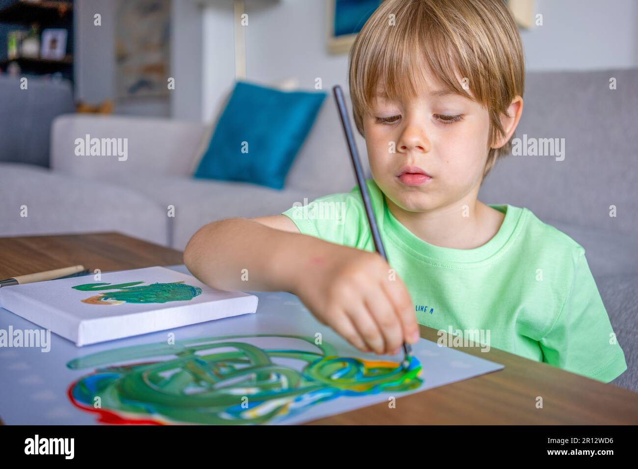 Cute child boy painting with a brush in living room. Stock Photo
