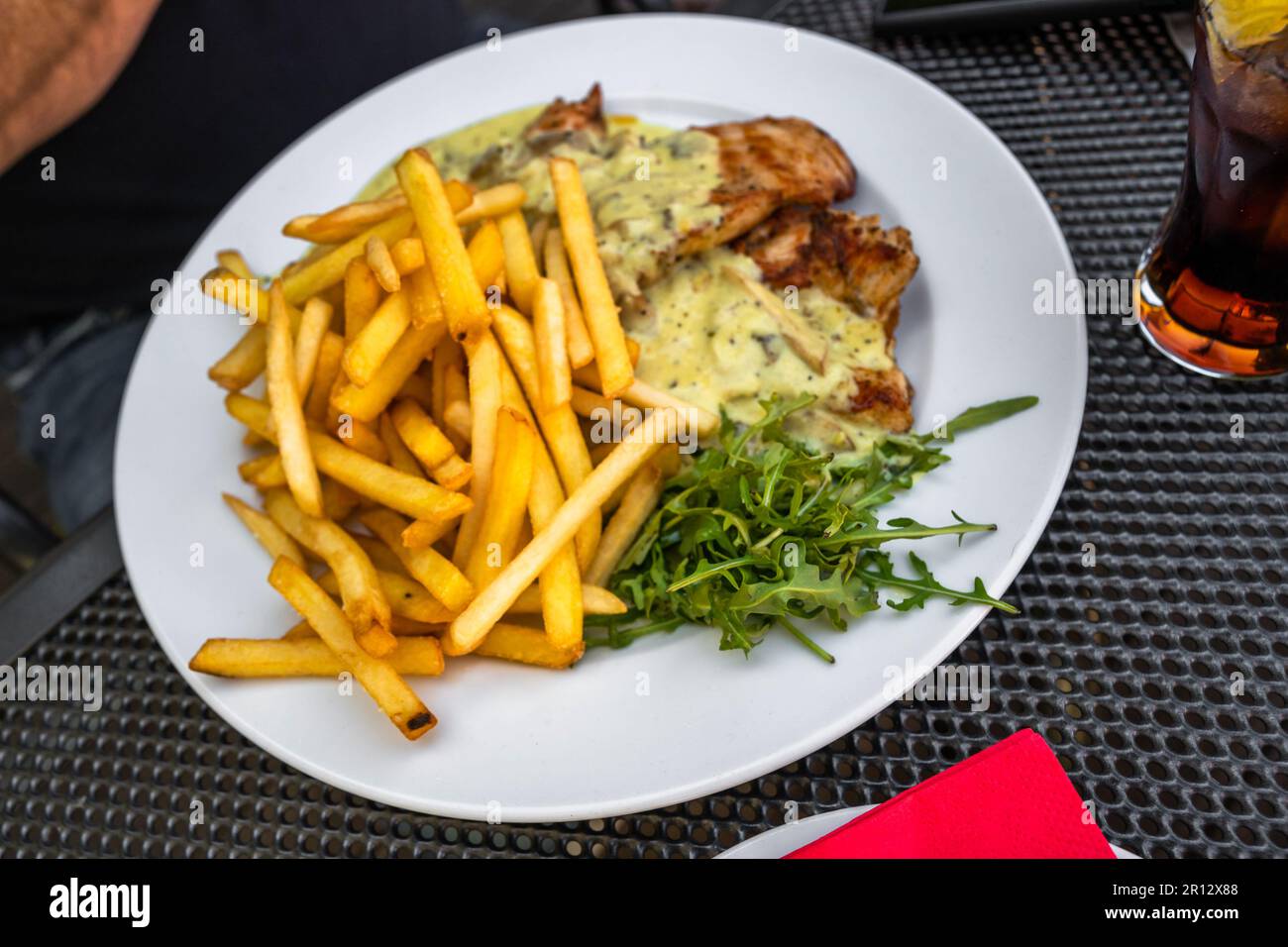 French fries with chicken meat, sauce and rucola leaf on plate, drink. Restaurant menu. Stock Photo