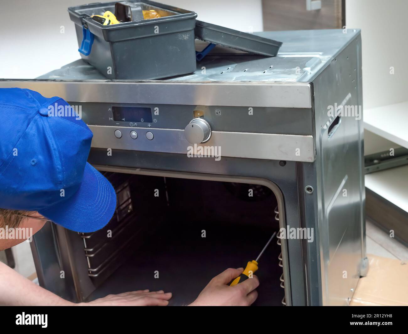 Serviceman dismantling parts of electric oven for easy repair access Stock Photo