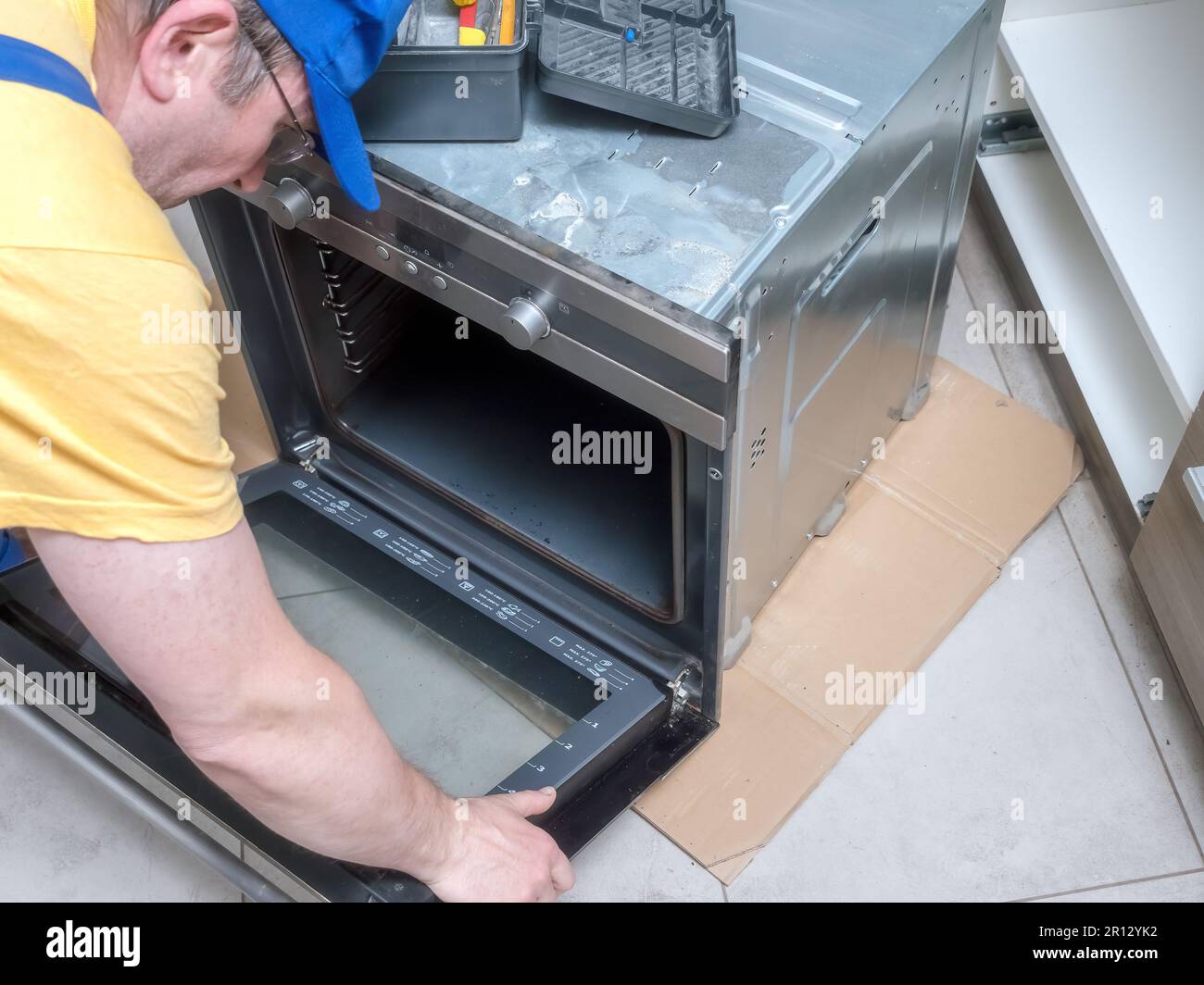 Serviceman removing electric oven door for easy repair access Stock Photo