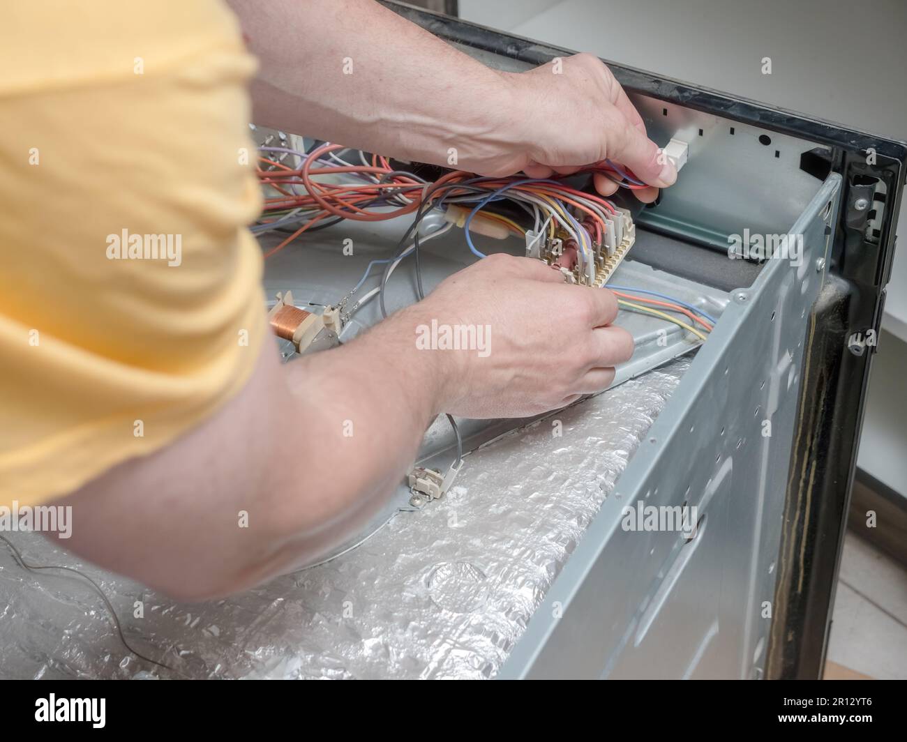 Serviceman locating faulty parts in the broken electric oven Stock Photo