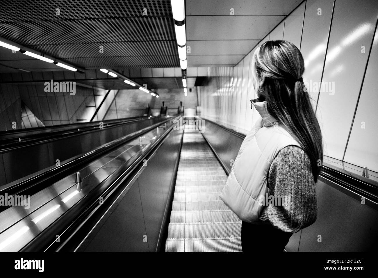 black-white image of a girl on an escalator to the underground Stock Photo