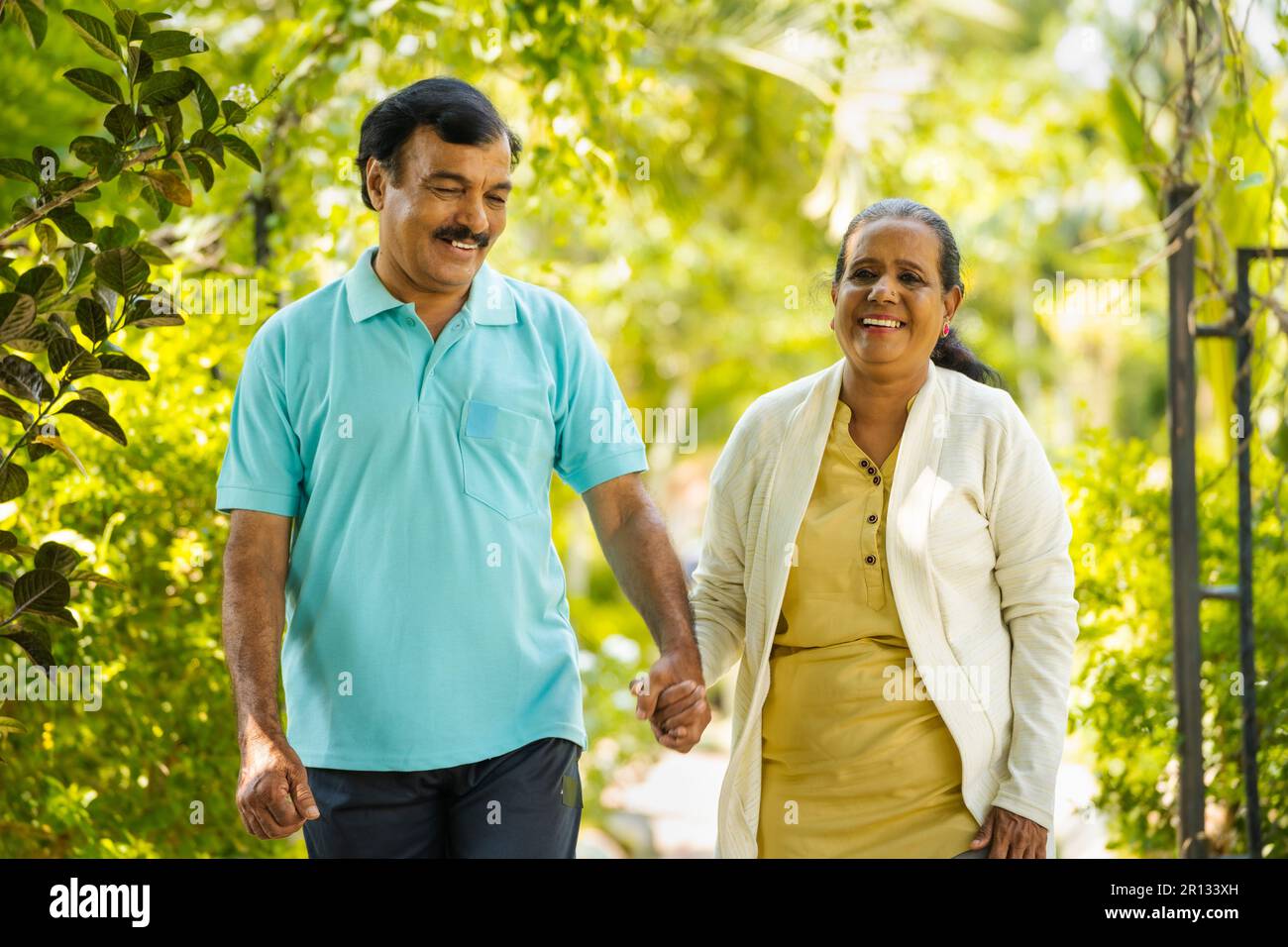 indian senior couple walking by talking each other at park - concept of ...