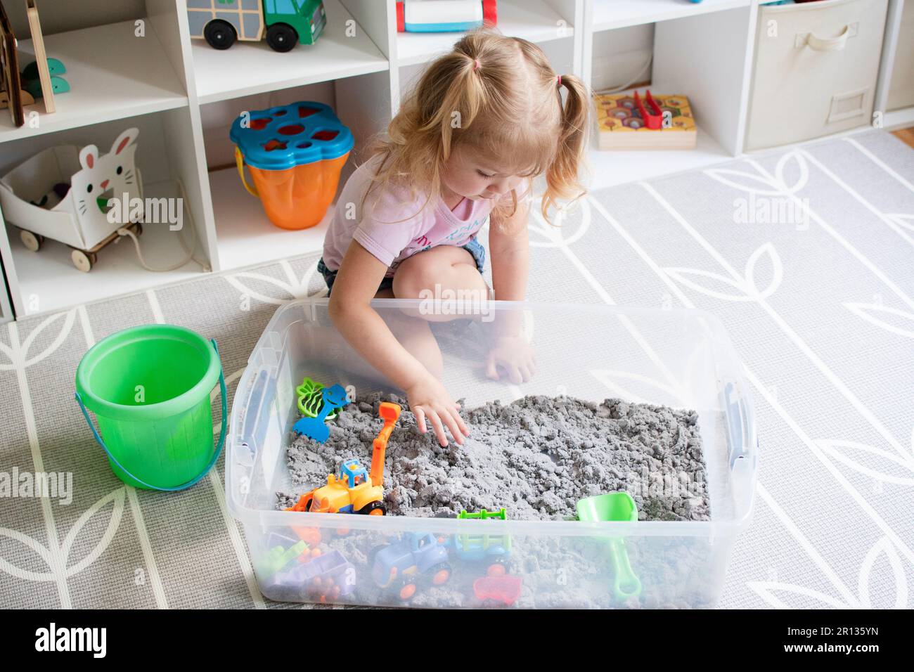 little girl playing with kinetic sand. Sensory box for kids Stock Photo
