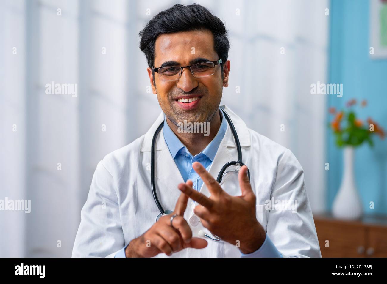 Confident indian doctor talking on video call by looking at camera from  hospital with patients - concept of online counseling, medical advice and  Stock Photo - Alamy