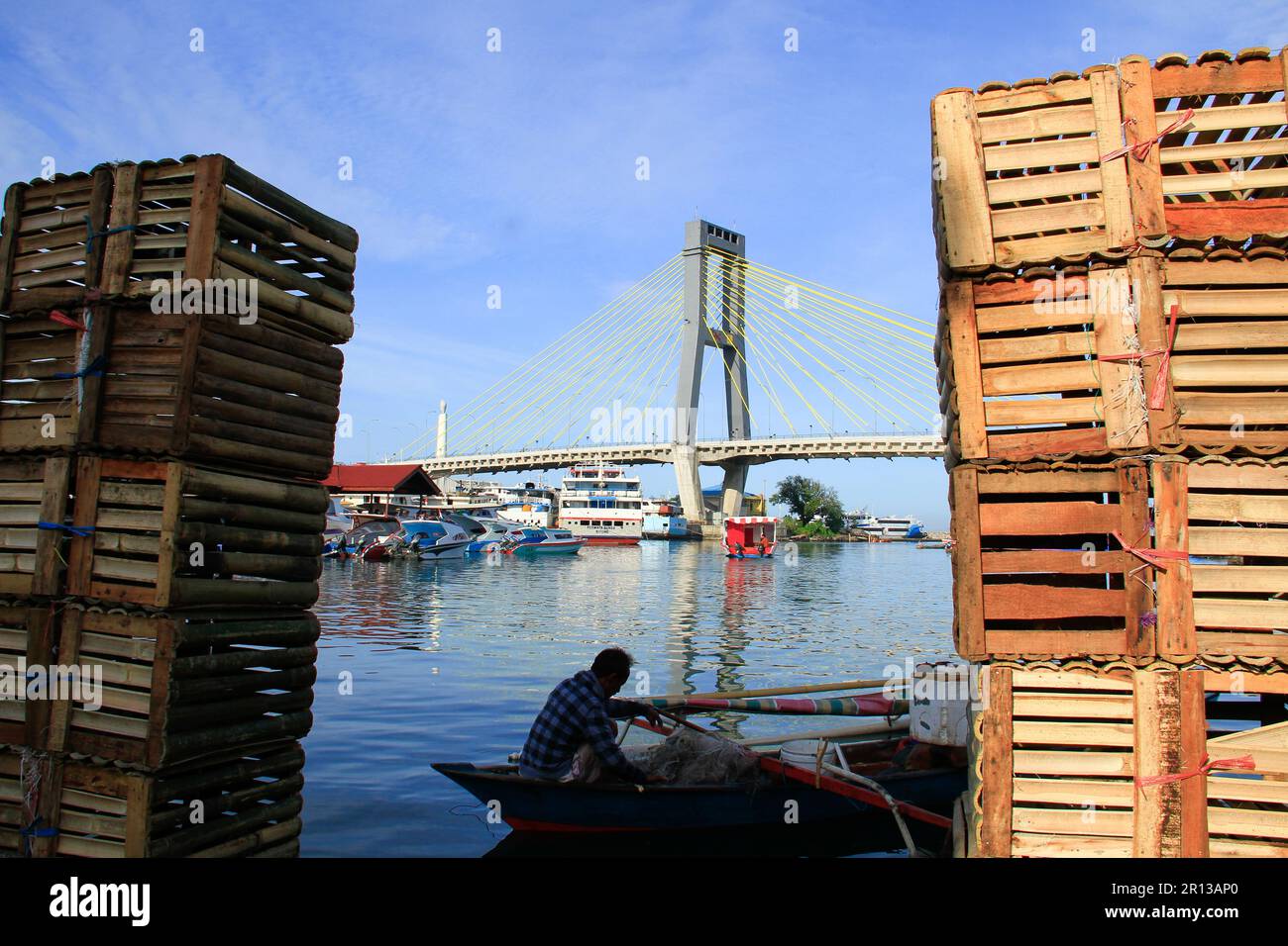 Fishing boats in the harbor with a magnificent bridge in the background, sea water and blue sky. Stock Photo