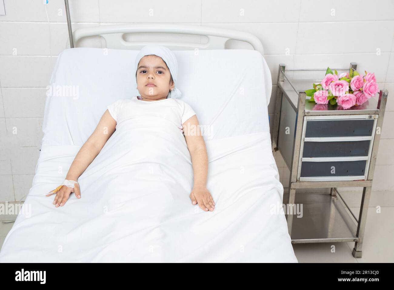 Smiling little girl child patient lying at hospital bed undergoing