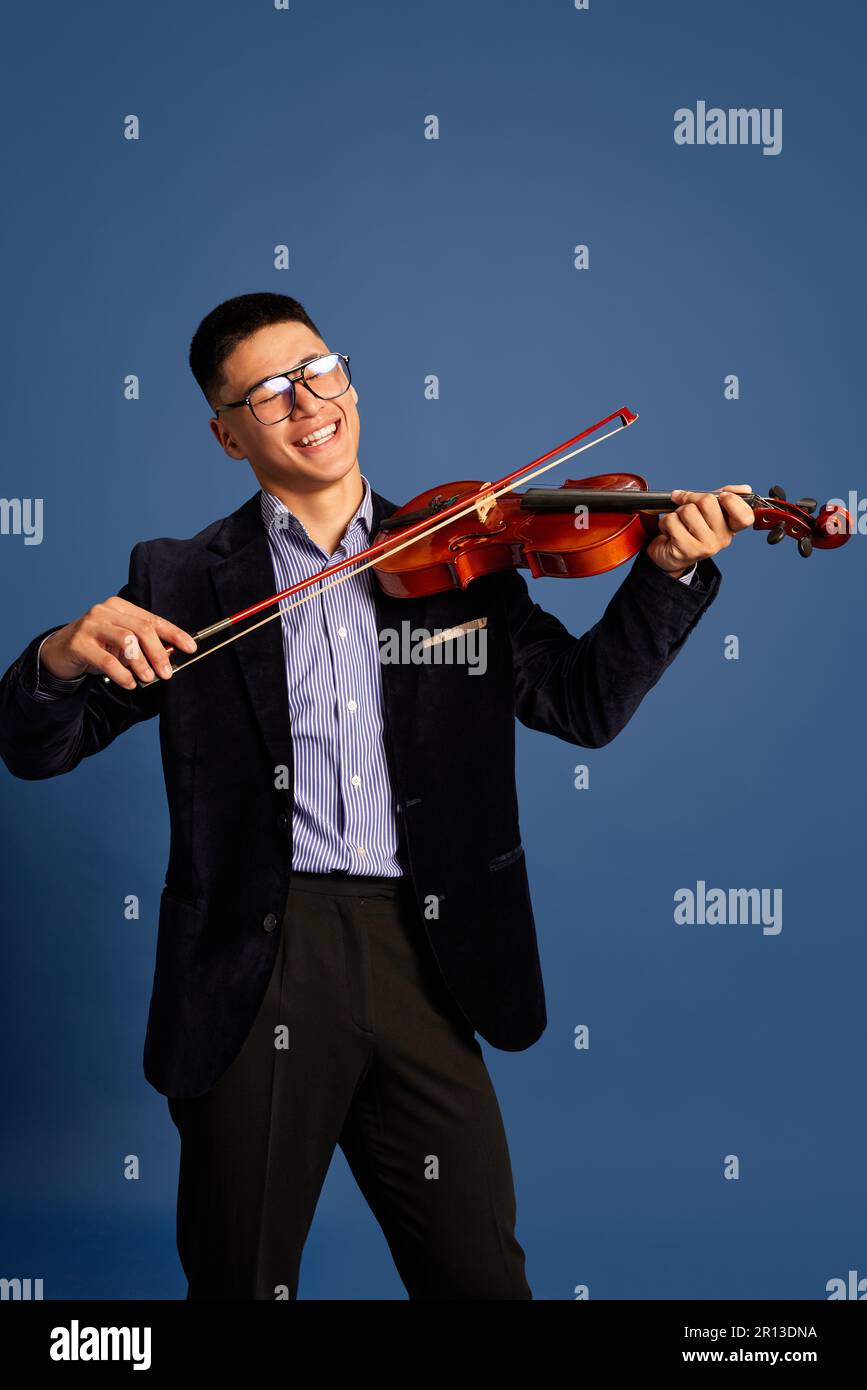 Portrait with handsome, young musicians, violinist wearing elegant suit and eyeglasses playing