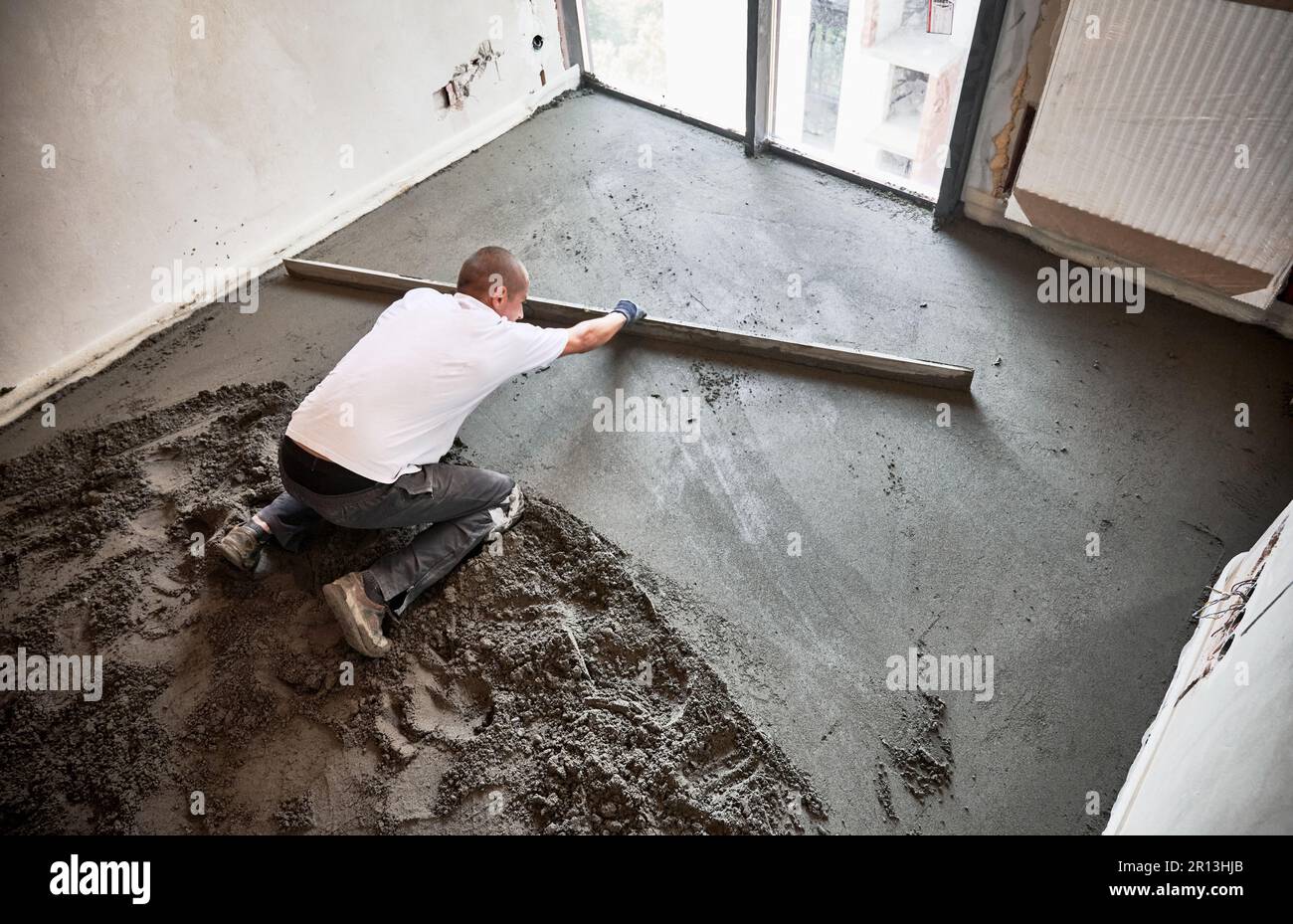 Top view of male construction worker placing screed rail on the floor