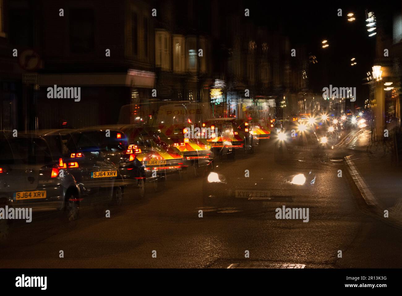 Multiple exposure photographs of Mill Road busy with traffic and a police van at night, Cambridge, UK Stock Photo