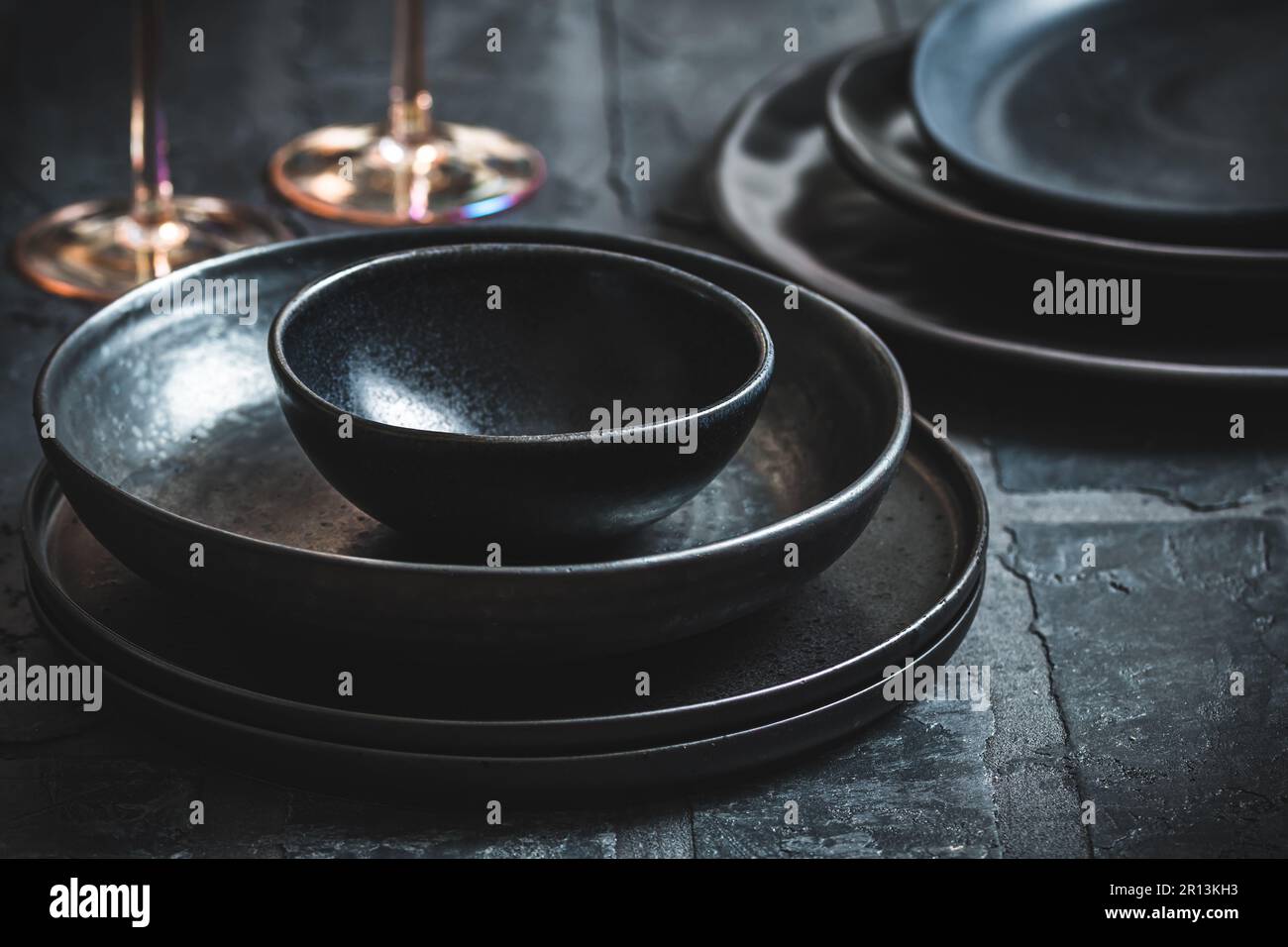 Black stoneware plates and bowls on a rustic black table Stock Photo