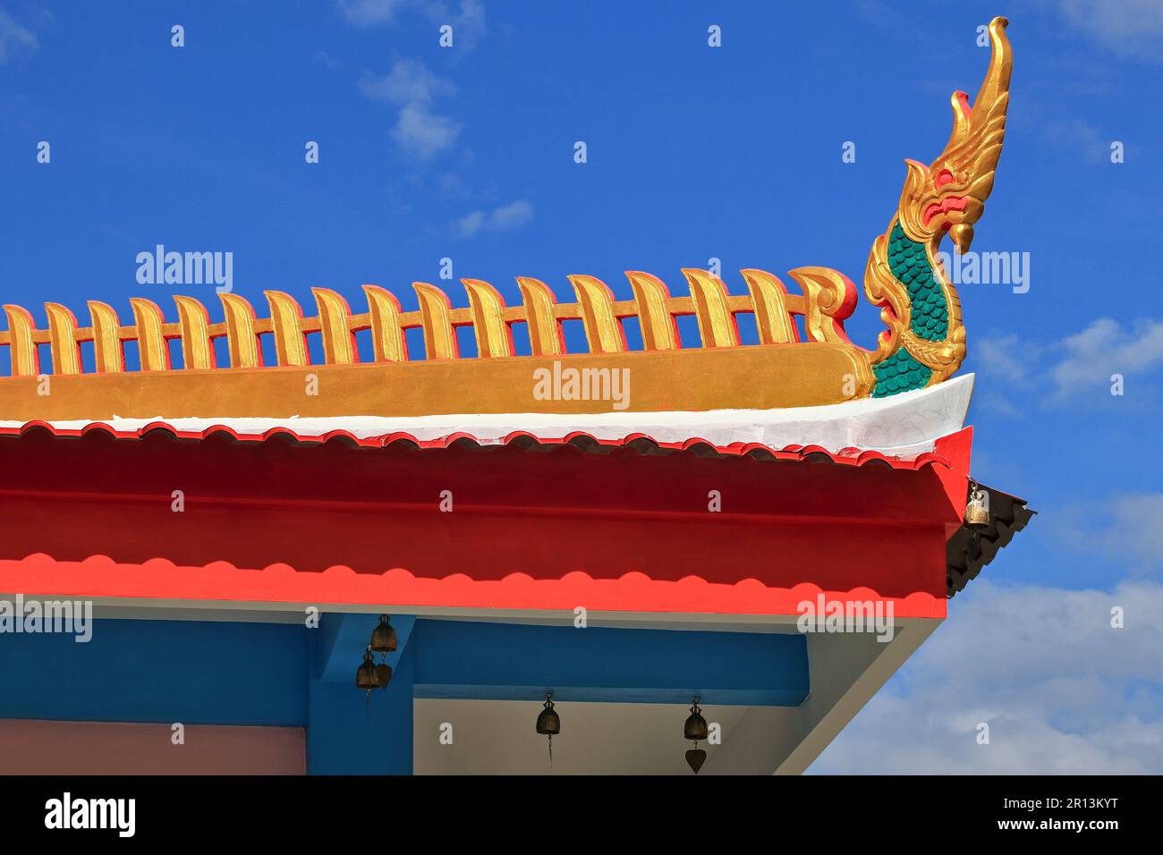 The golden Naga motif on the roof of a Thai temple is part of a structure known as Naga Sadung. with blue sky background Stock Photo