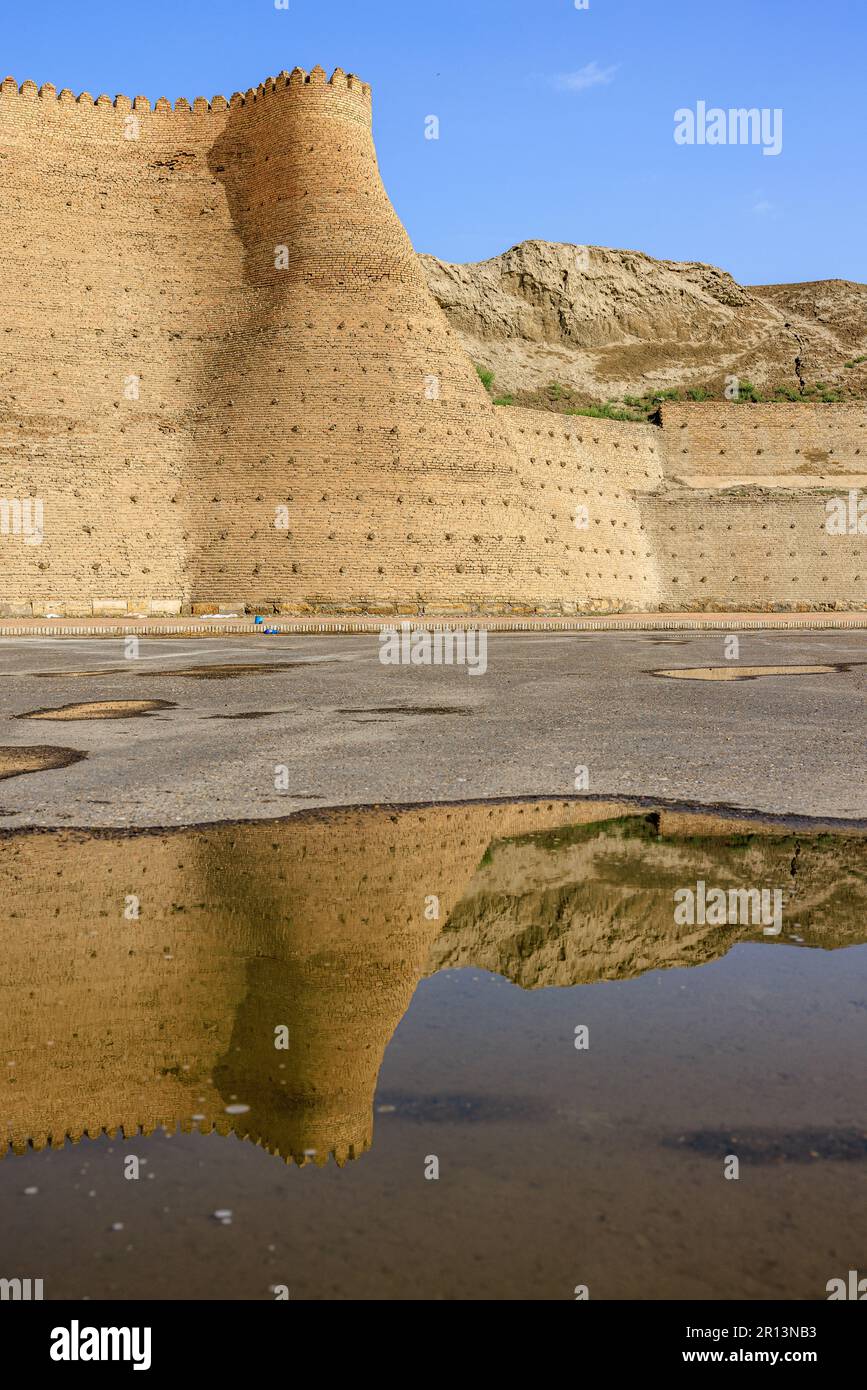 massive walls of the ark of bukhara are reflected in puddle of water after recent rain Stock Photo