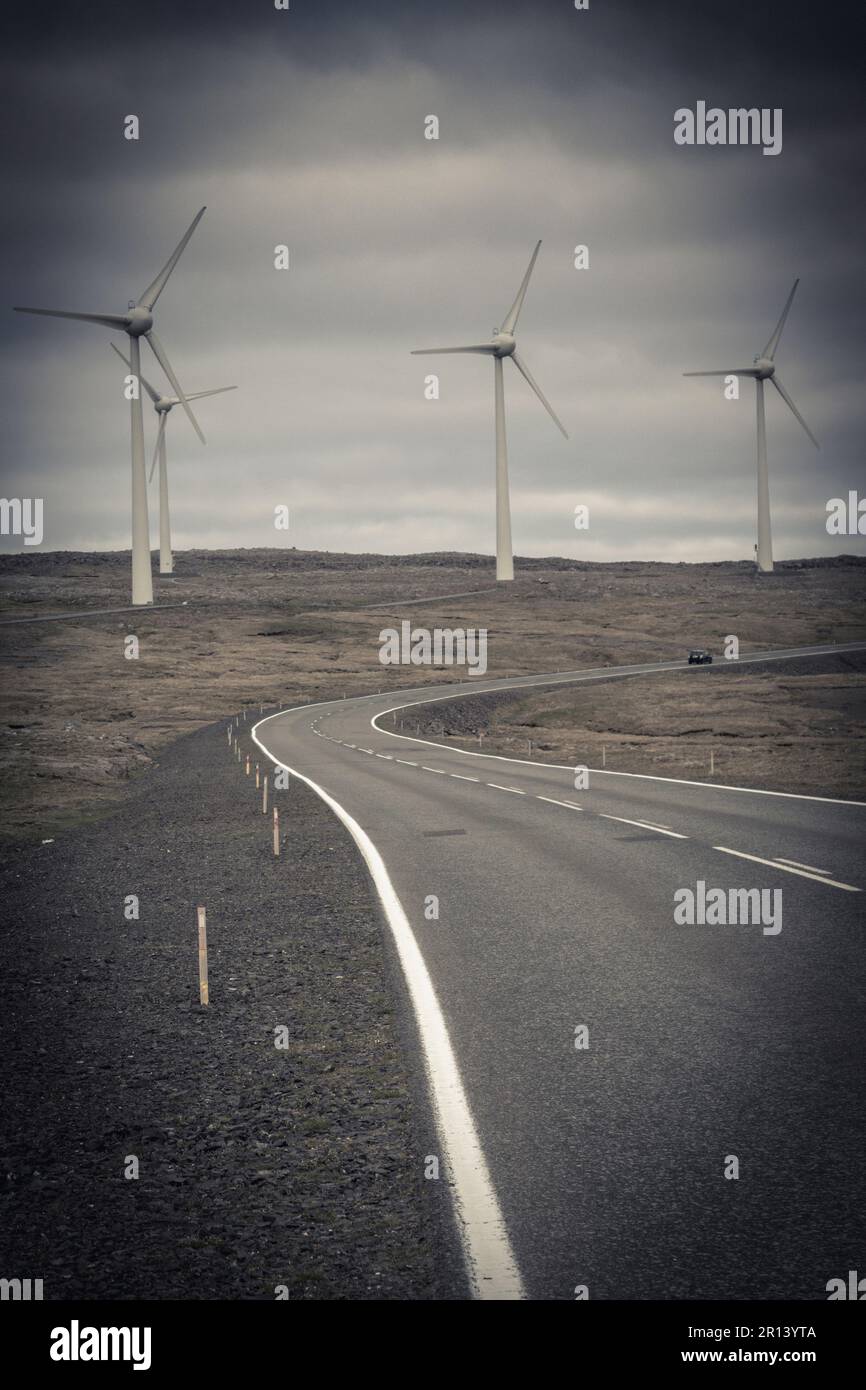 desolate road and wind turbines in the background Stock Photo