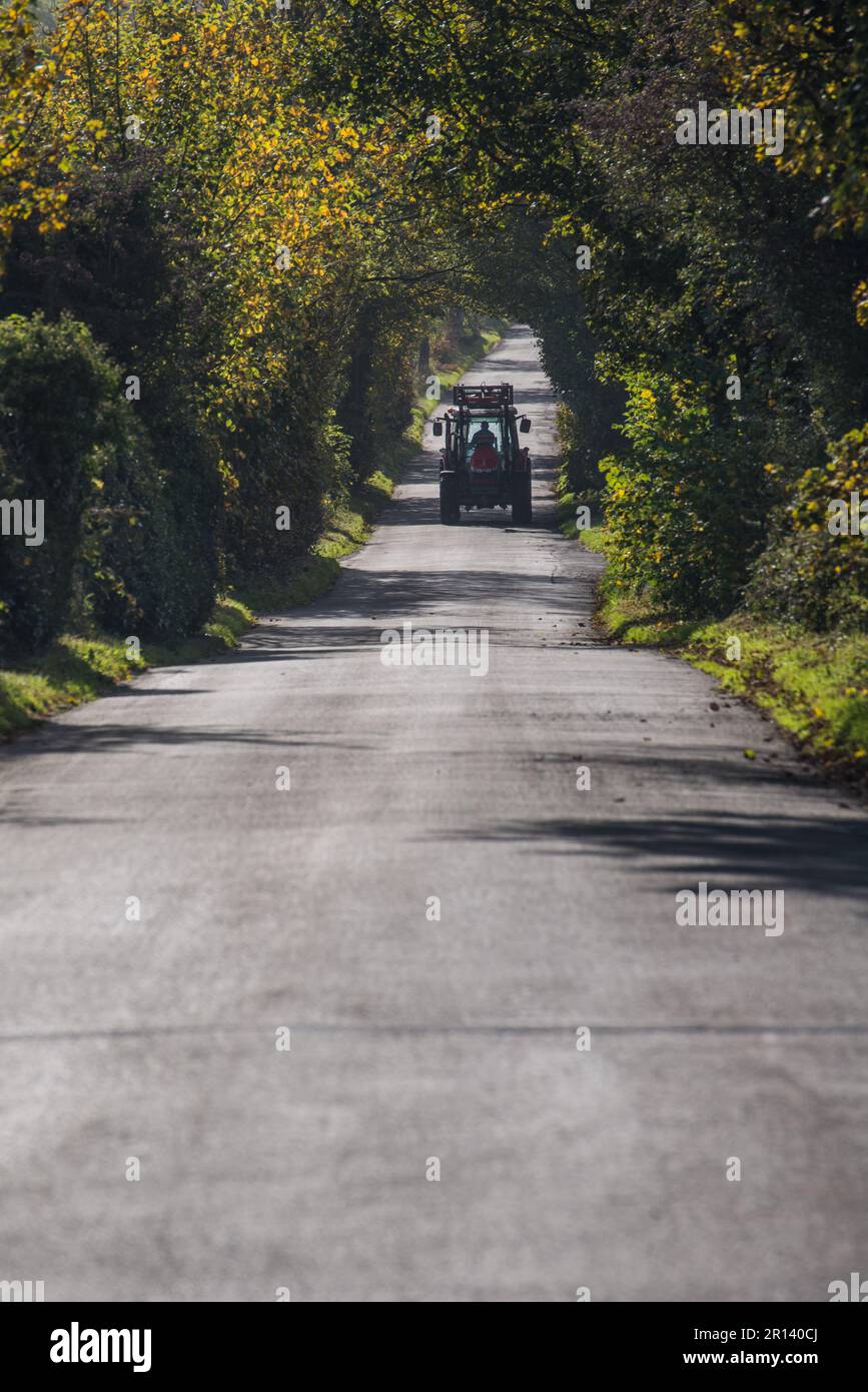 A tractor driving along a leafy lane near Belper, Derbyshire, England Stock Photo