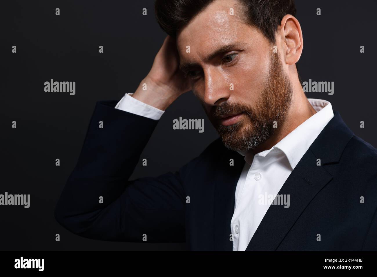 Handsome bearded man looking down on black background Stock Photo
